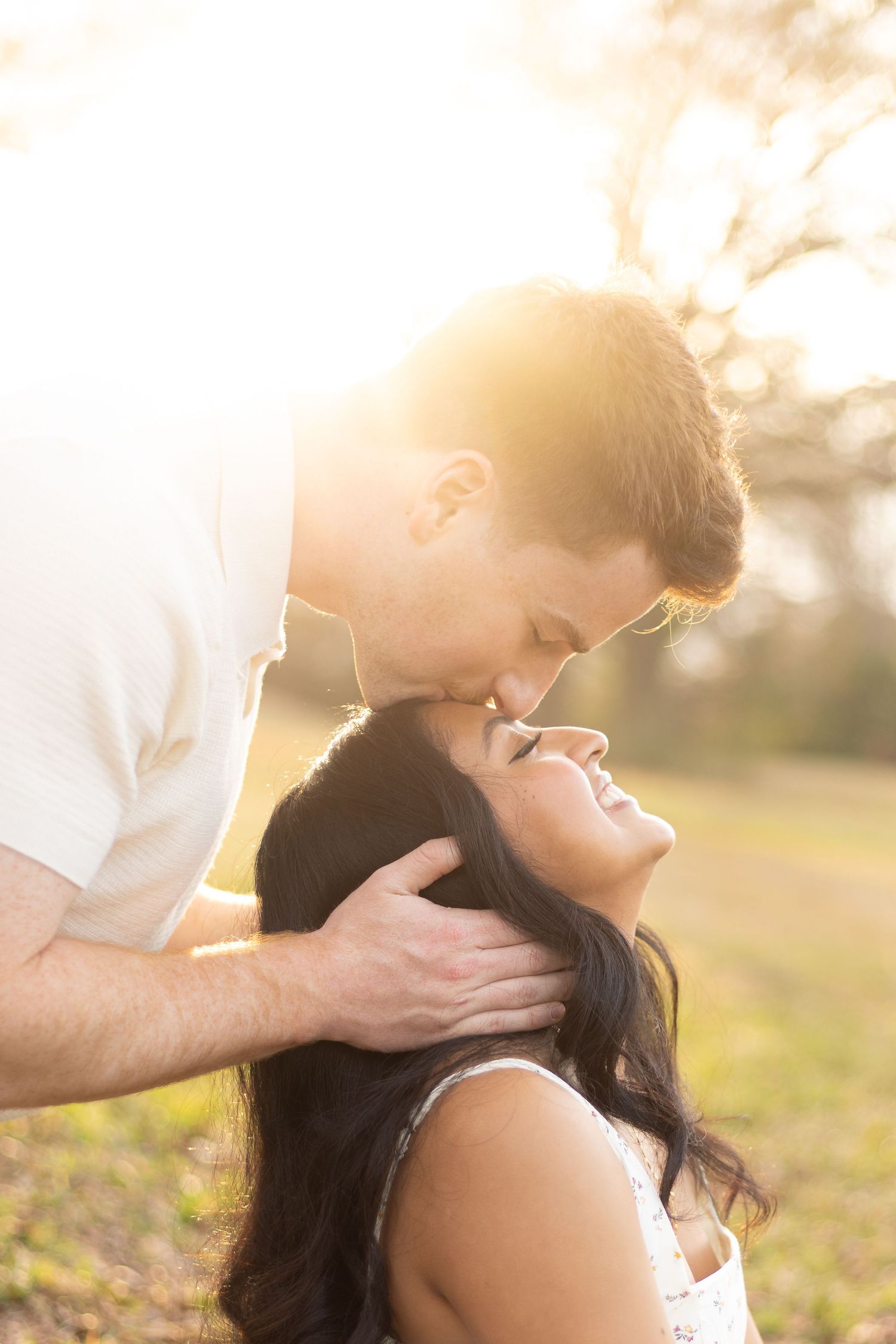 Romantic couple sharing a tender moment in golden sunlight outdoors.