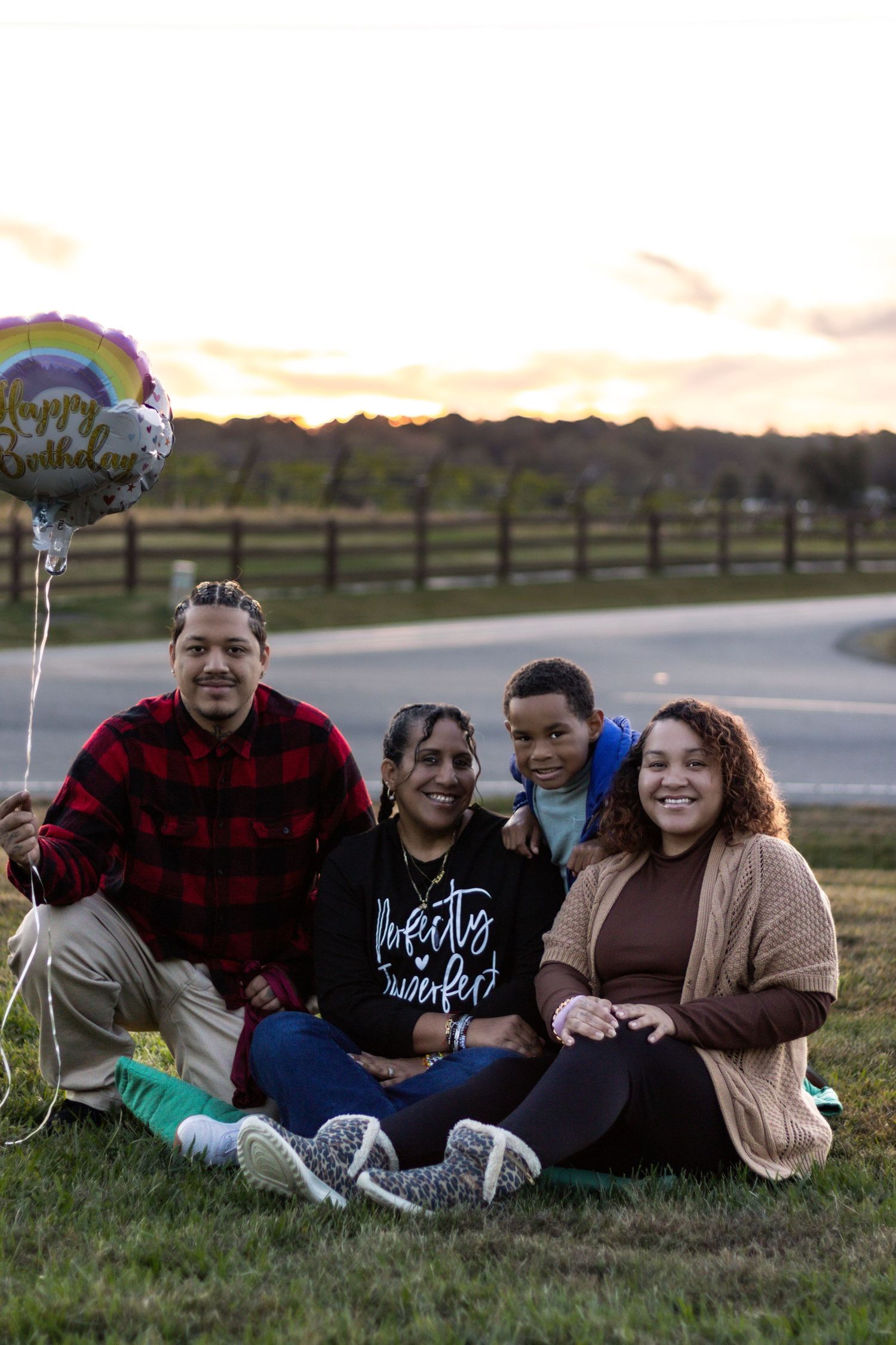 Group relaxing on grassy hill during sunset with buffalo plaid and casual attire.