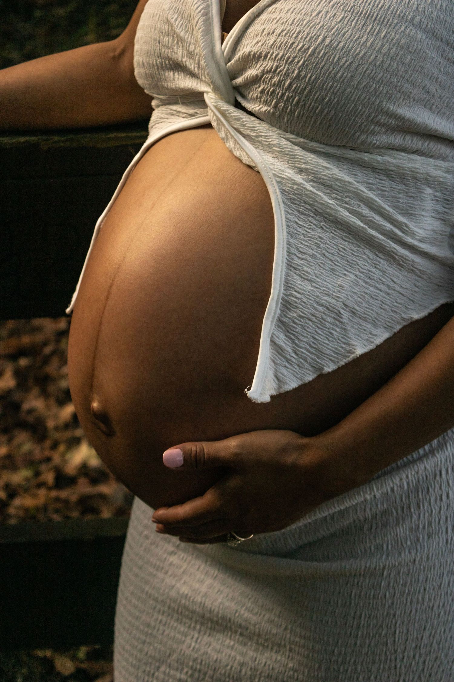 A series of close-up shots showing a pregnant belly in a white dress against a dark background.