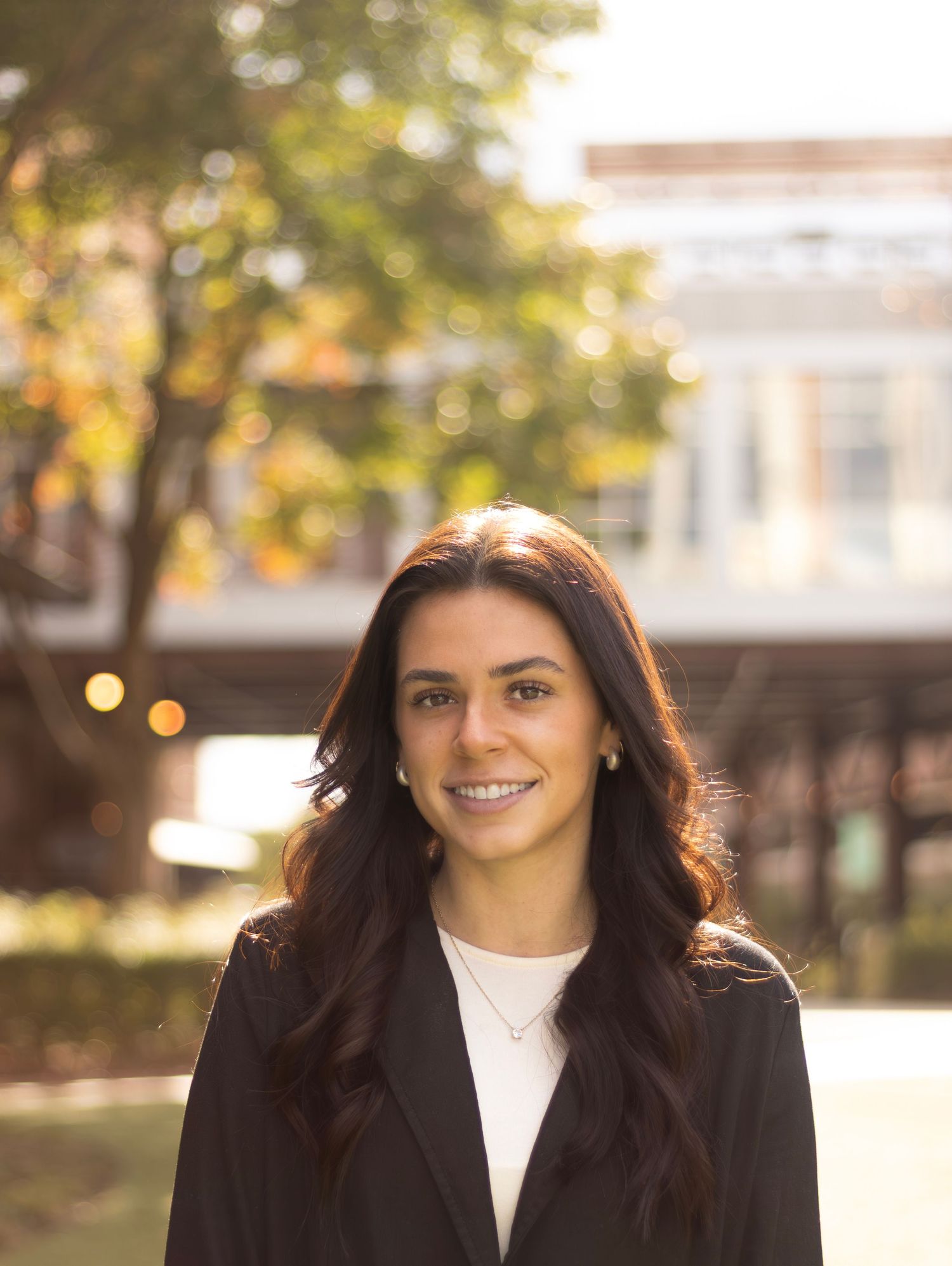 Professional outdoor portraits of woman in black blazer with autumn background.