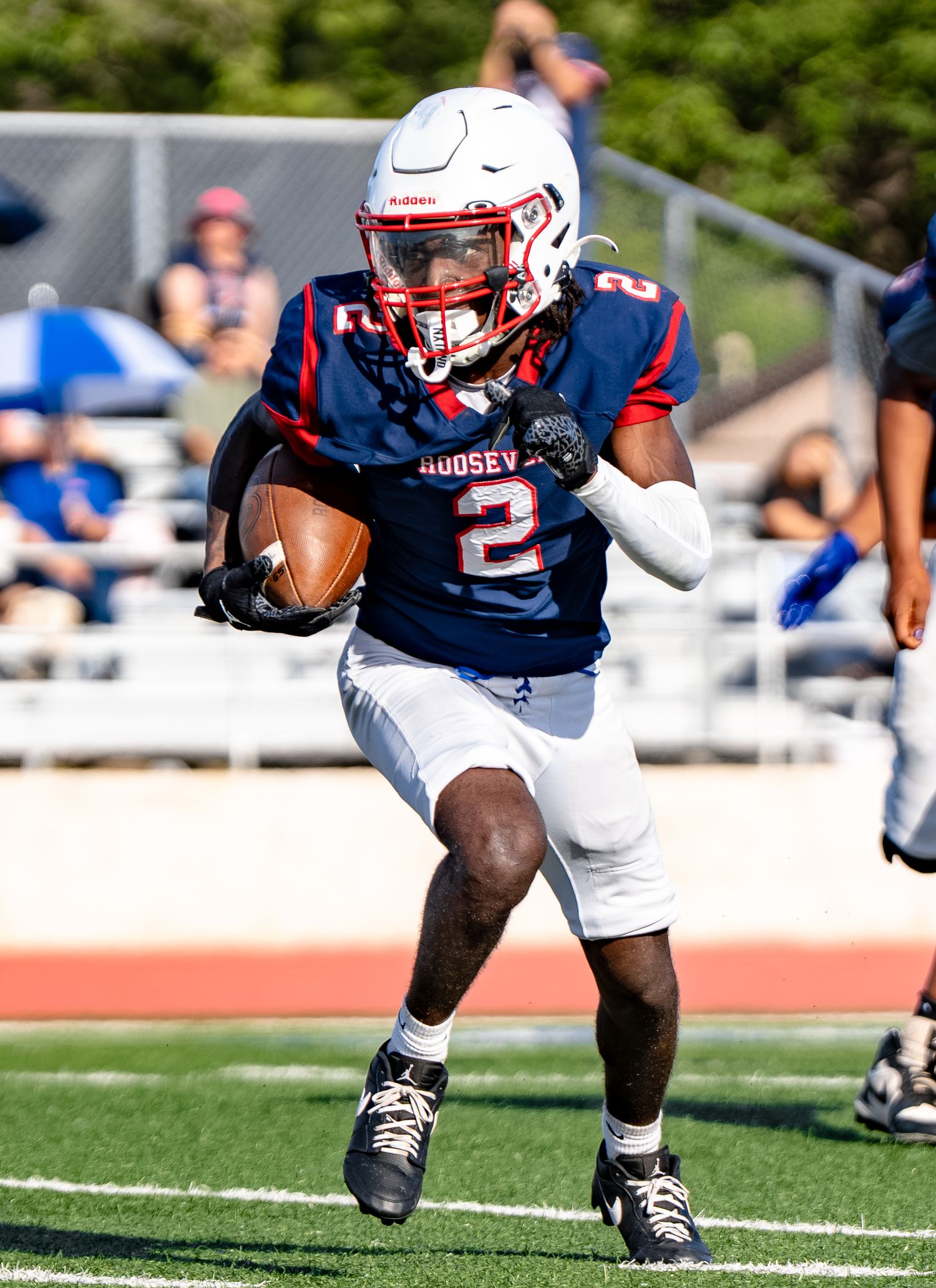 Roosevelt high school football player number 2 carries ball in blue red uniform.