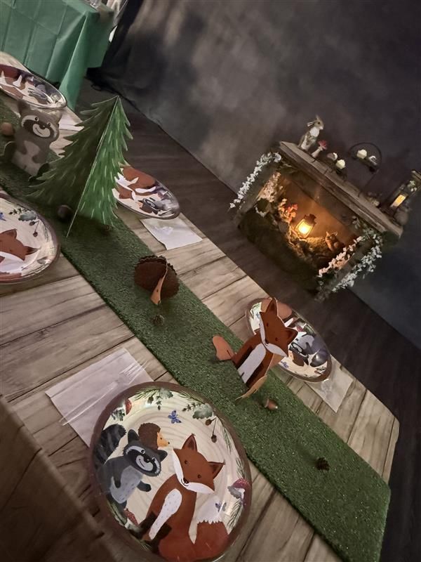 Overhead view of a miniature Christmas nativity scene with wooden pathway, green grass runner, animal figures, and illuminated stable.