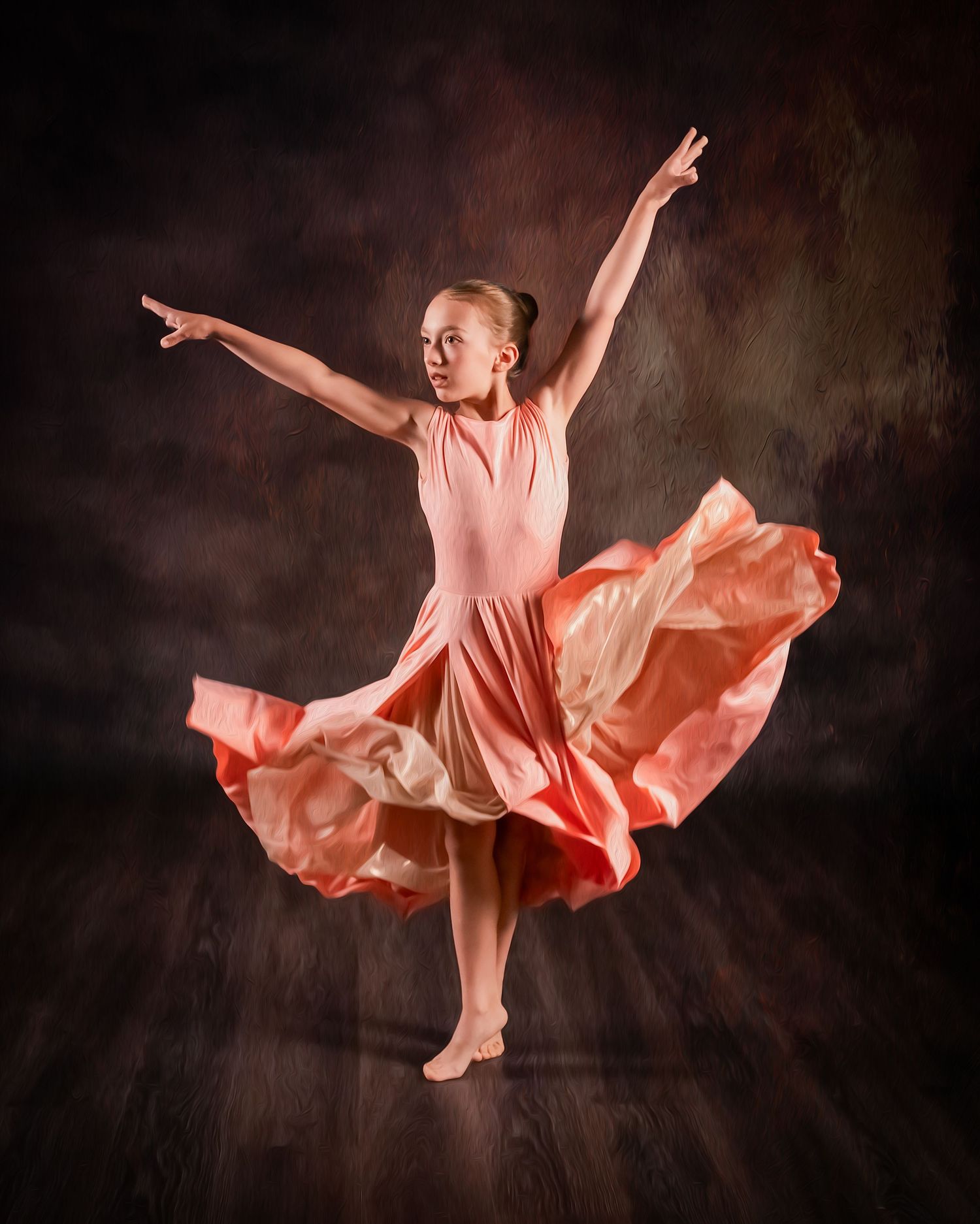 Young dancer in flowing coral dress performs graceful ballet pose against dark studio backdrop.