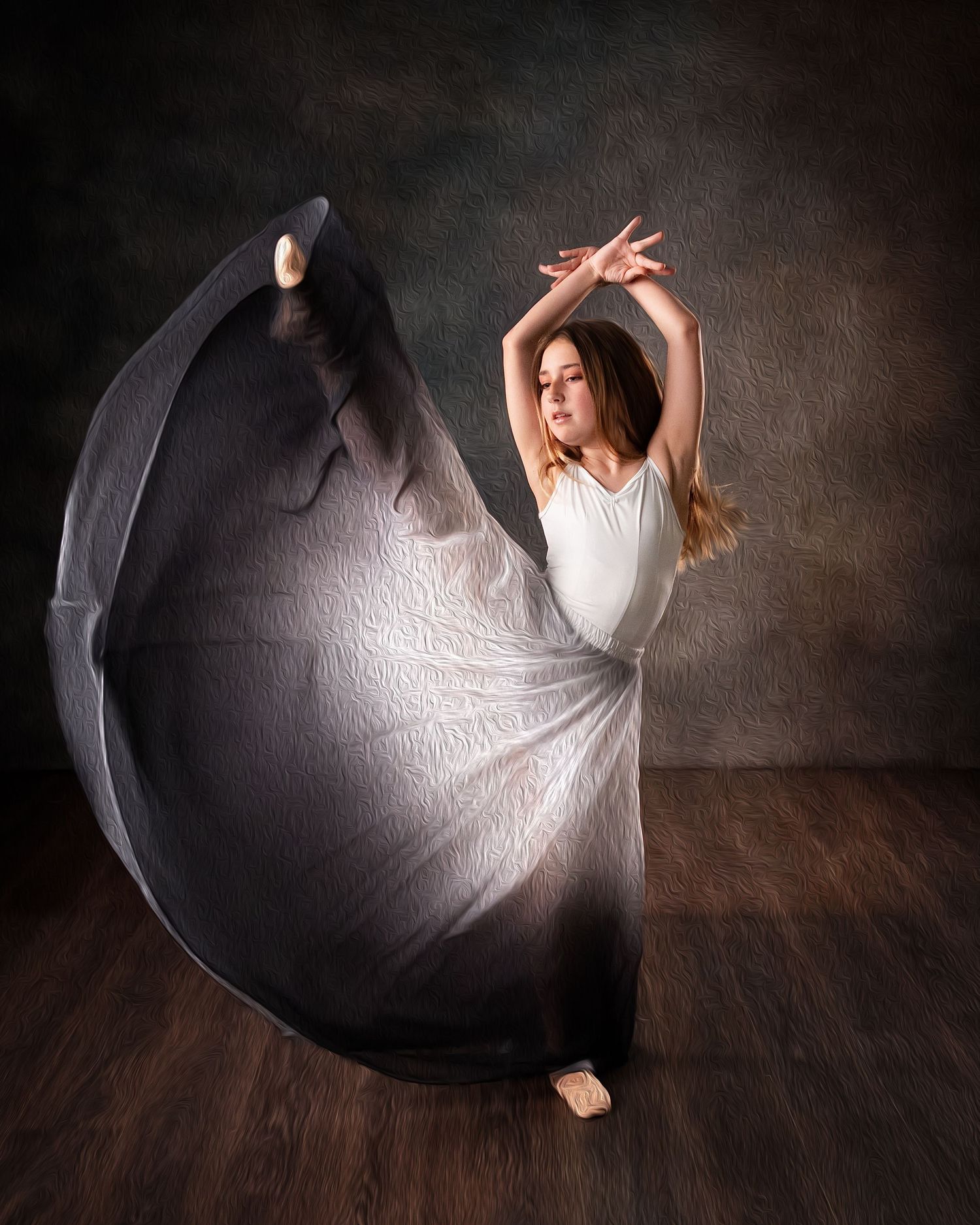 A graceful ballerina poses in a flowing black and white gown, arms raised elegantly in a studio setting.