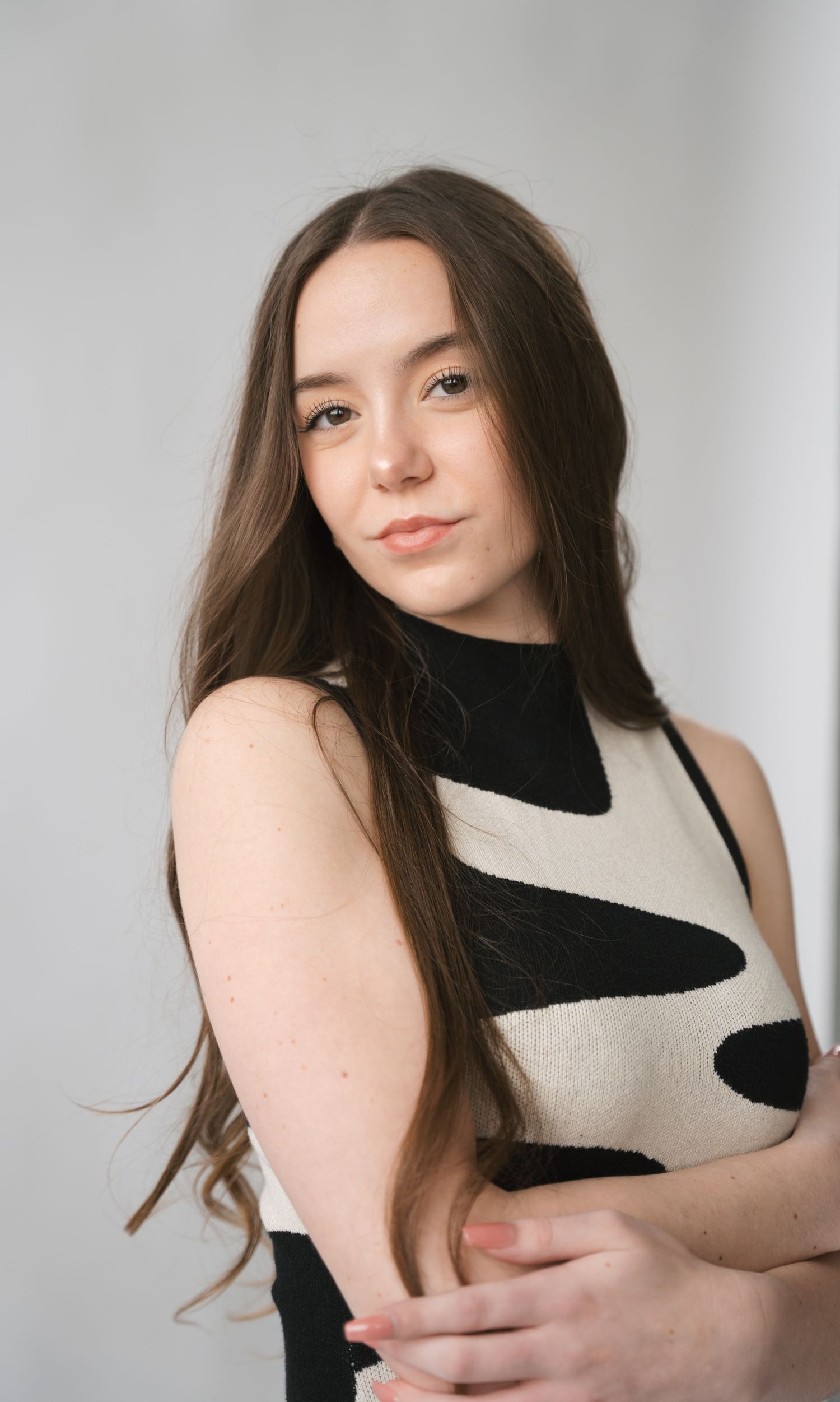 Model wearing black and cream sleeveless top poses against white studio background.