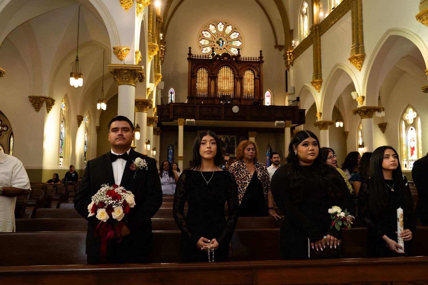 Interior of an illuminated church with vaulted ceilings and Gothic architectural details during a wedding ceremony.