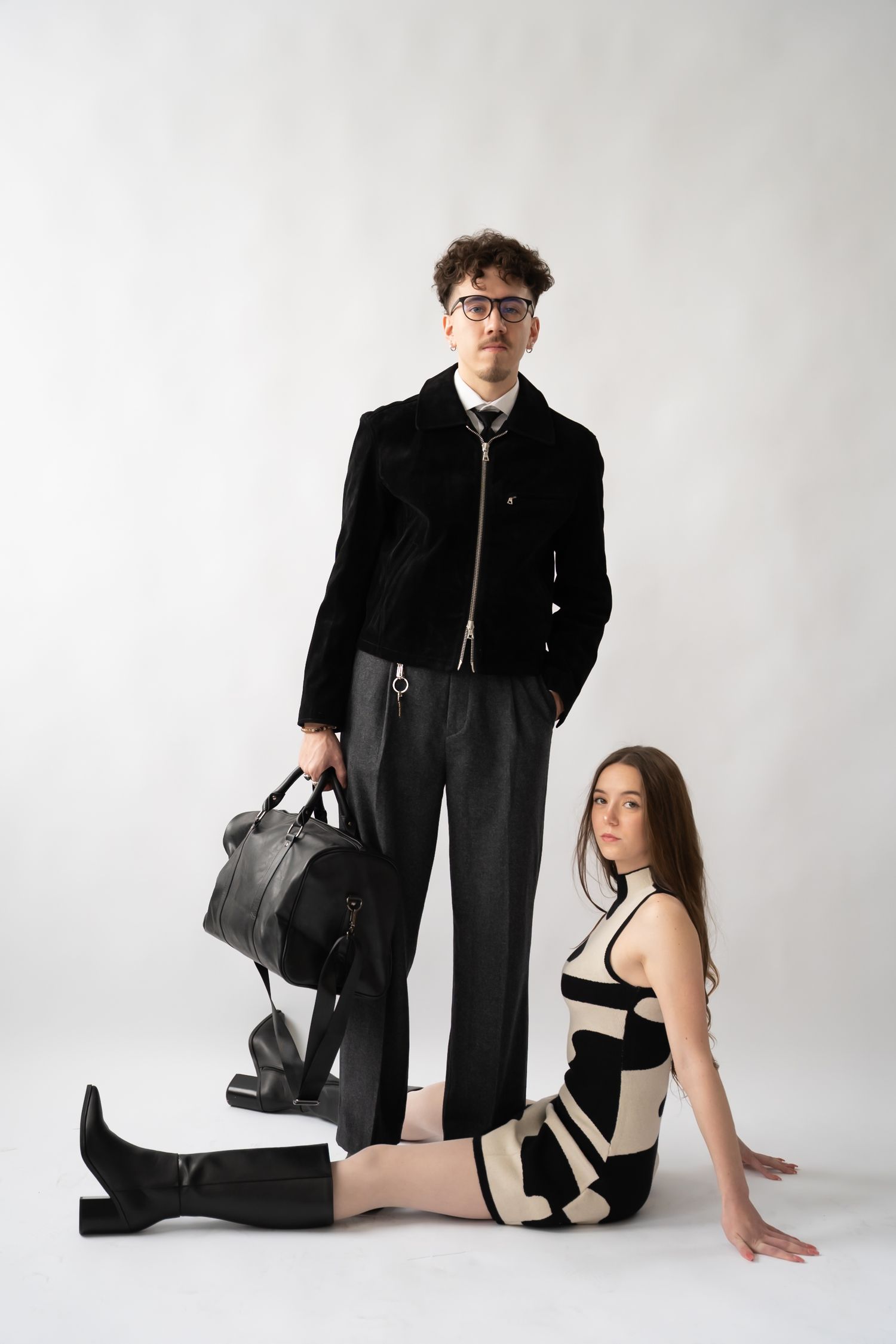 Fashion editorial featuring two models in monochromatic outfits against white studio background.