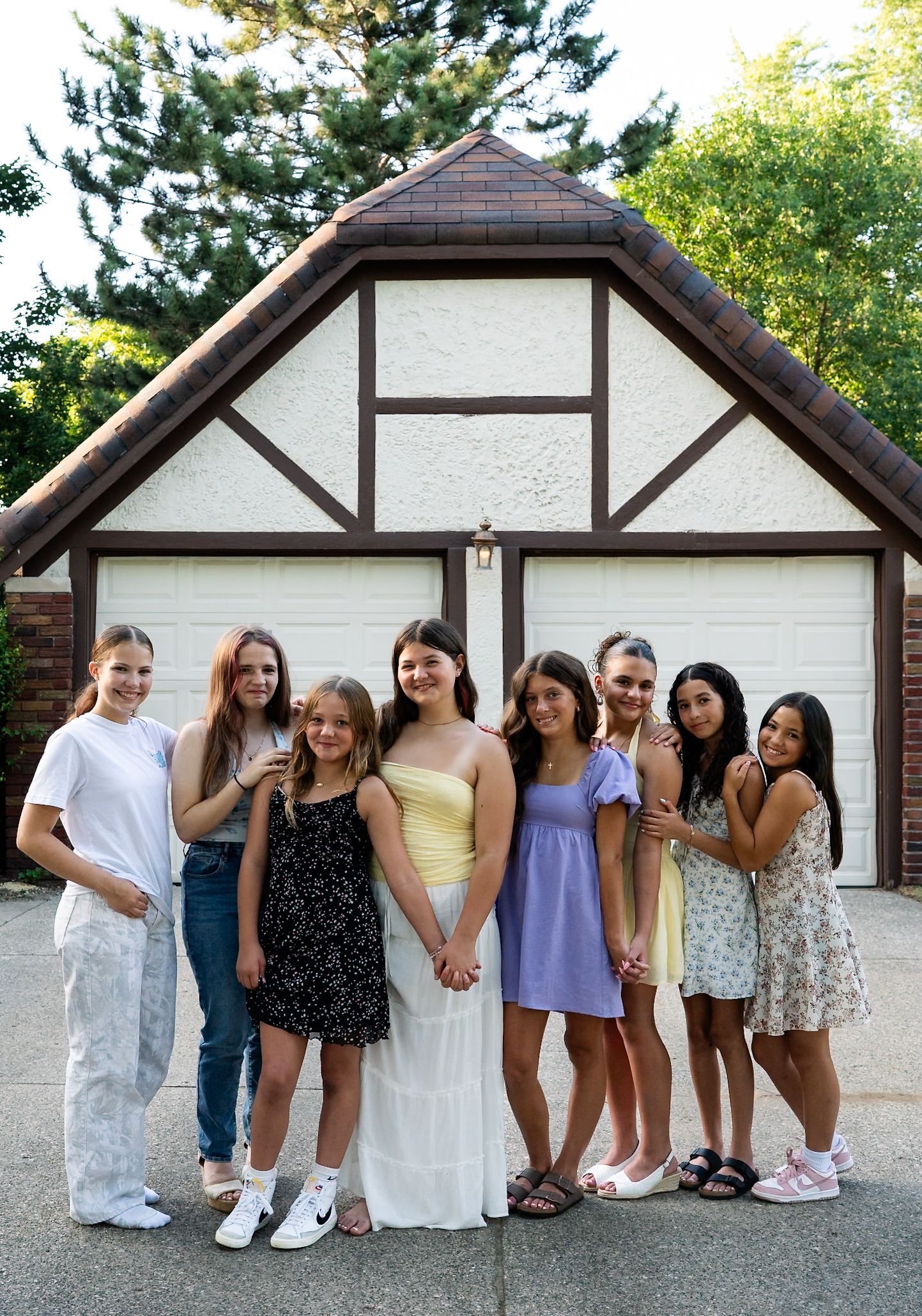 Group photo of friends lined up against white Tudor-style building exterior.