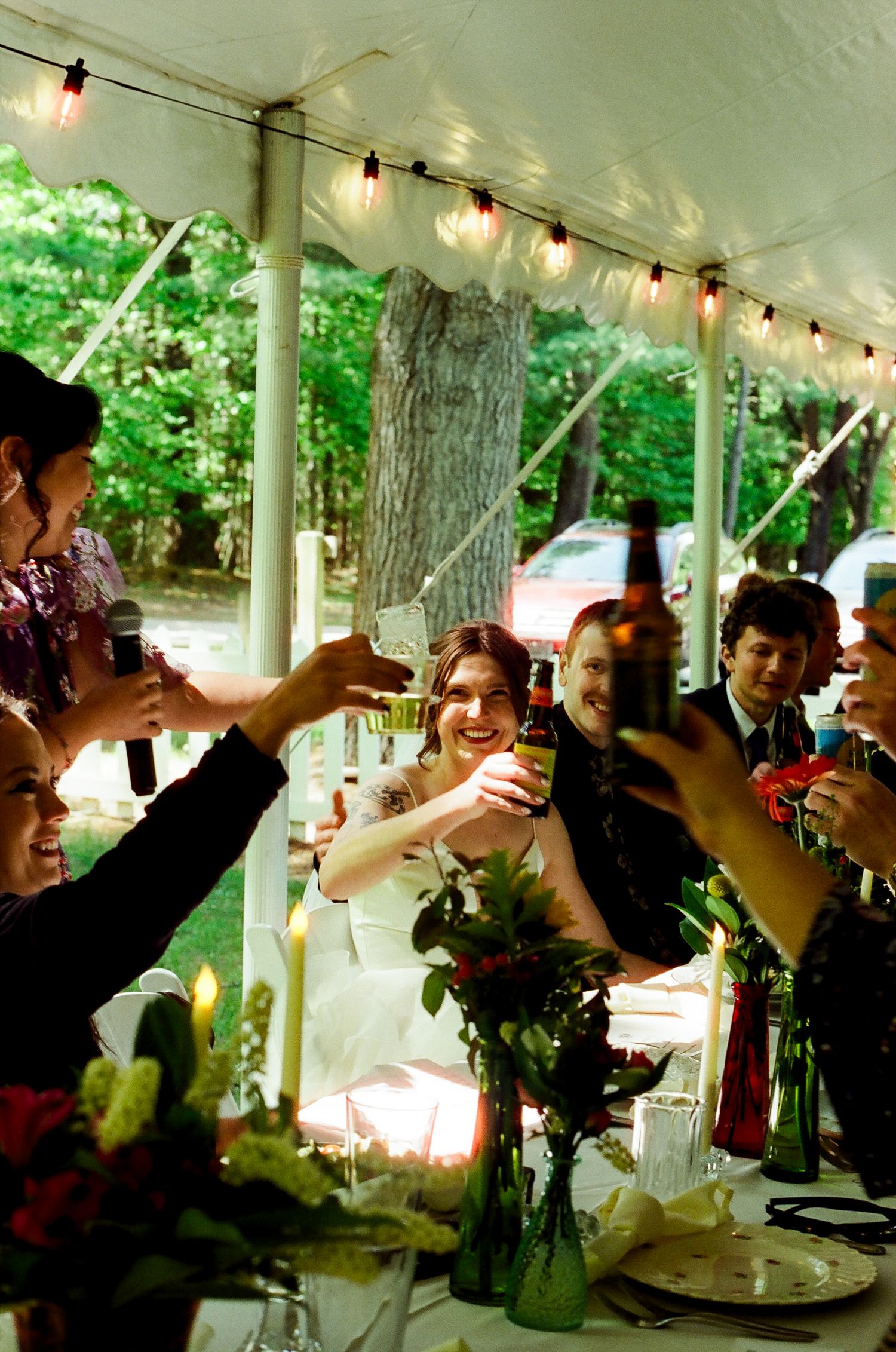 Wedding guests raise their glasses in a celebratory toast during an outdoor reception.