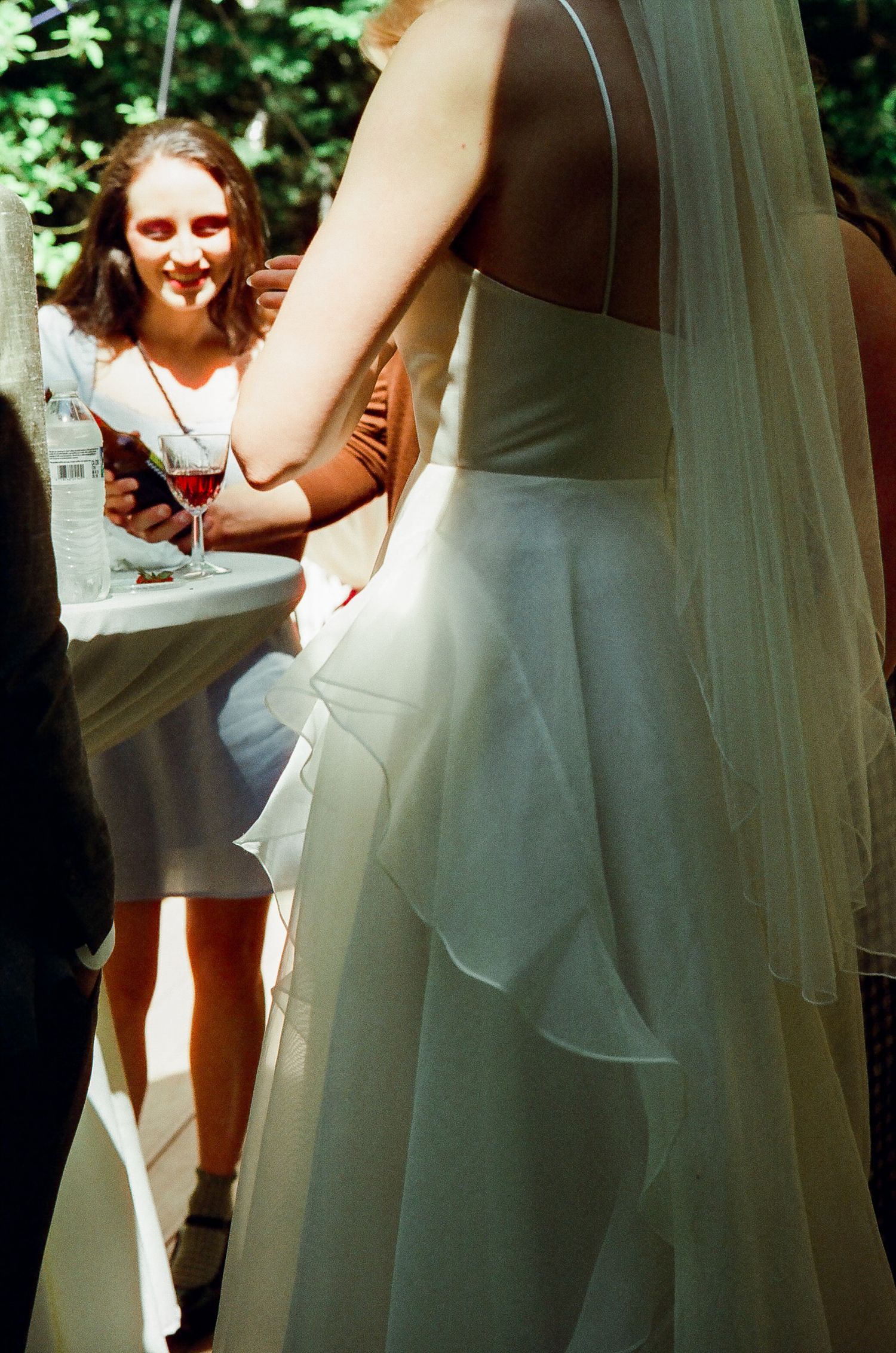 A flowing white wedding dress with delicate veil details captured in natural sunlight.