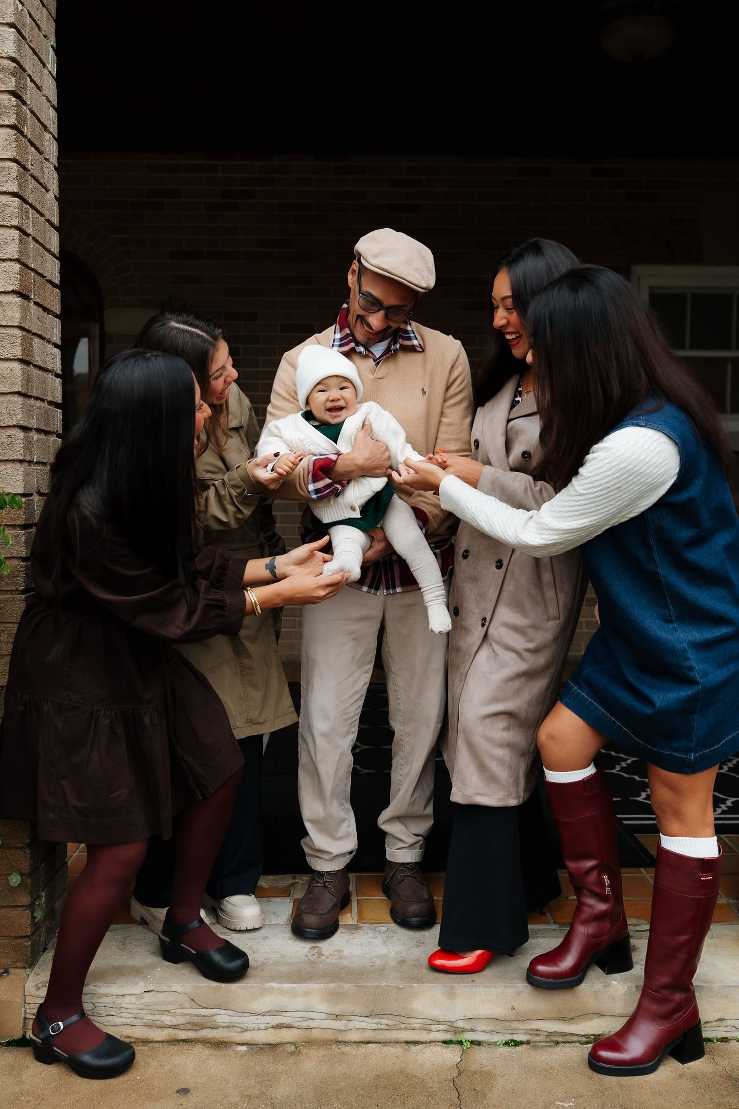 Group gathered on doorstep wearing coordinated fall outfits and rain boots.