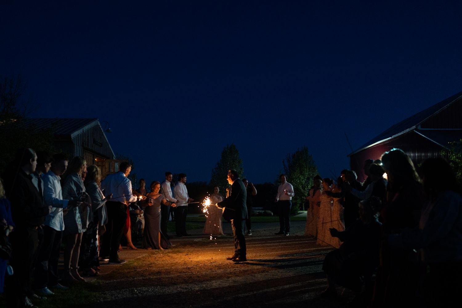 A nighttime wedding celebration with guests gathered outdoors under the stars.