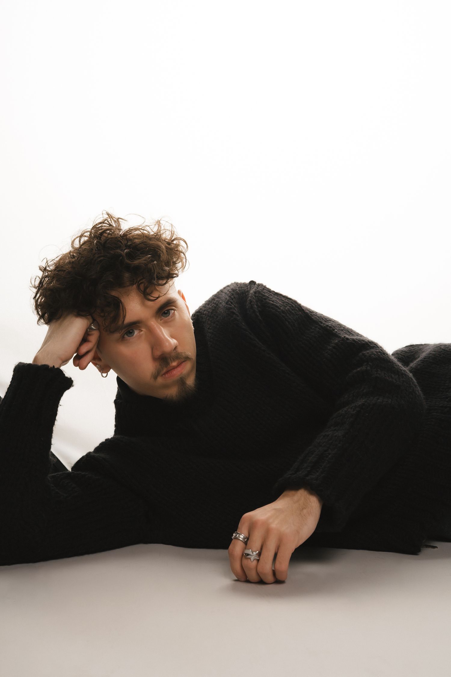 Artistic portrait series of person in black clothing lying on white surface.