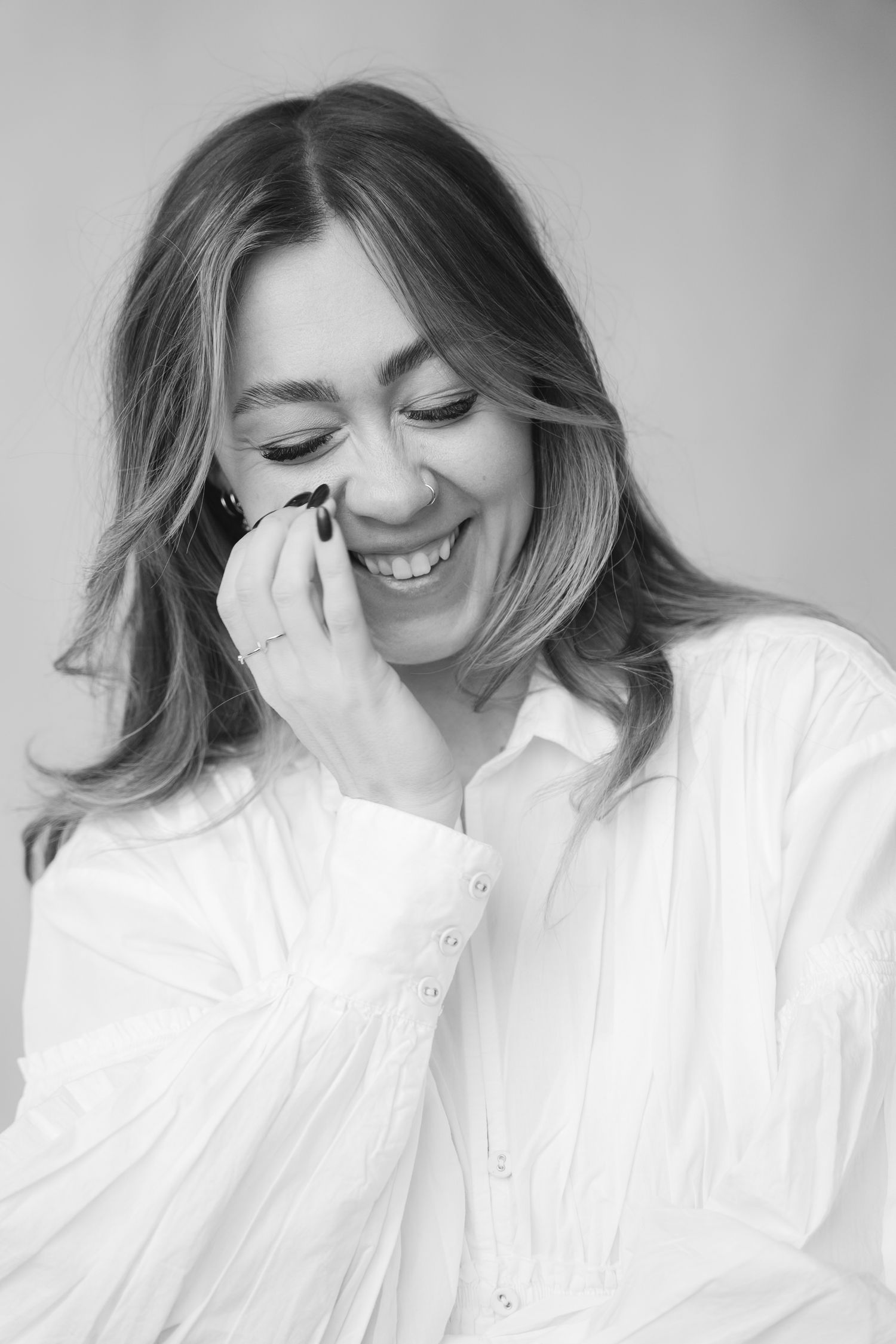 Candid black and white portrait showing joyful laughter in white button-down shirt.