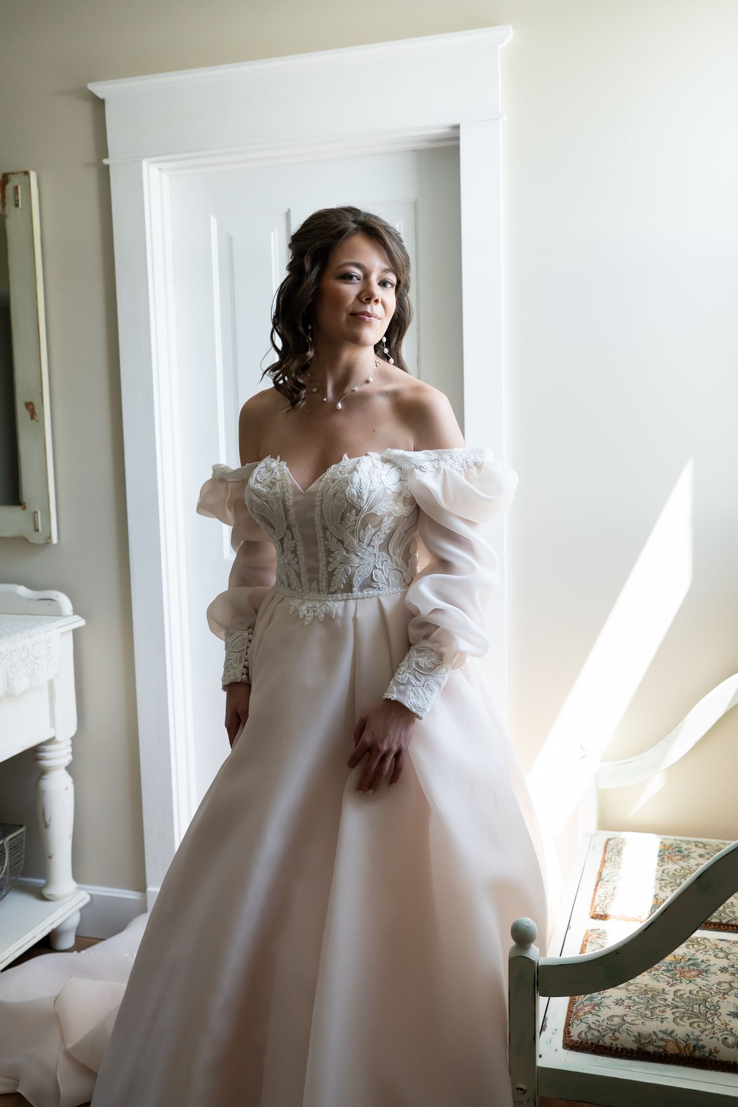 A beautiful white wedding dress with delicate lace details and puff sleeves is captured in soft natural light.
