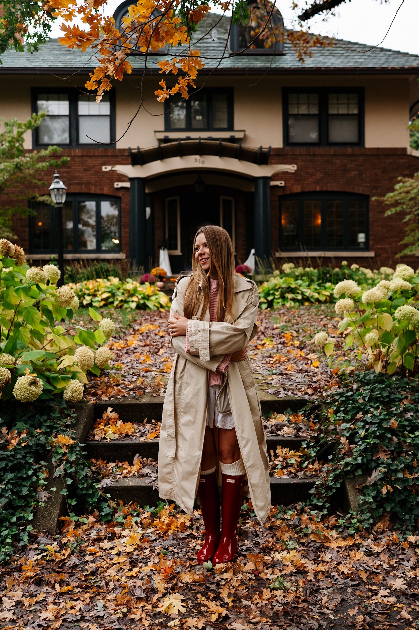 Fashion photography in front of a craftsman style house with fall foliage and hydrangea bushes.