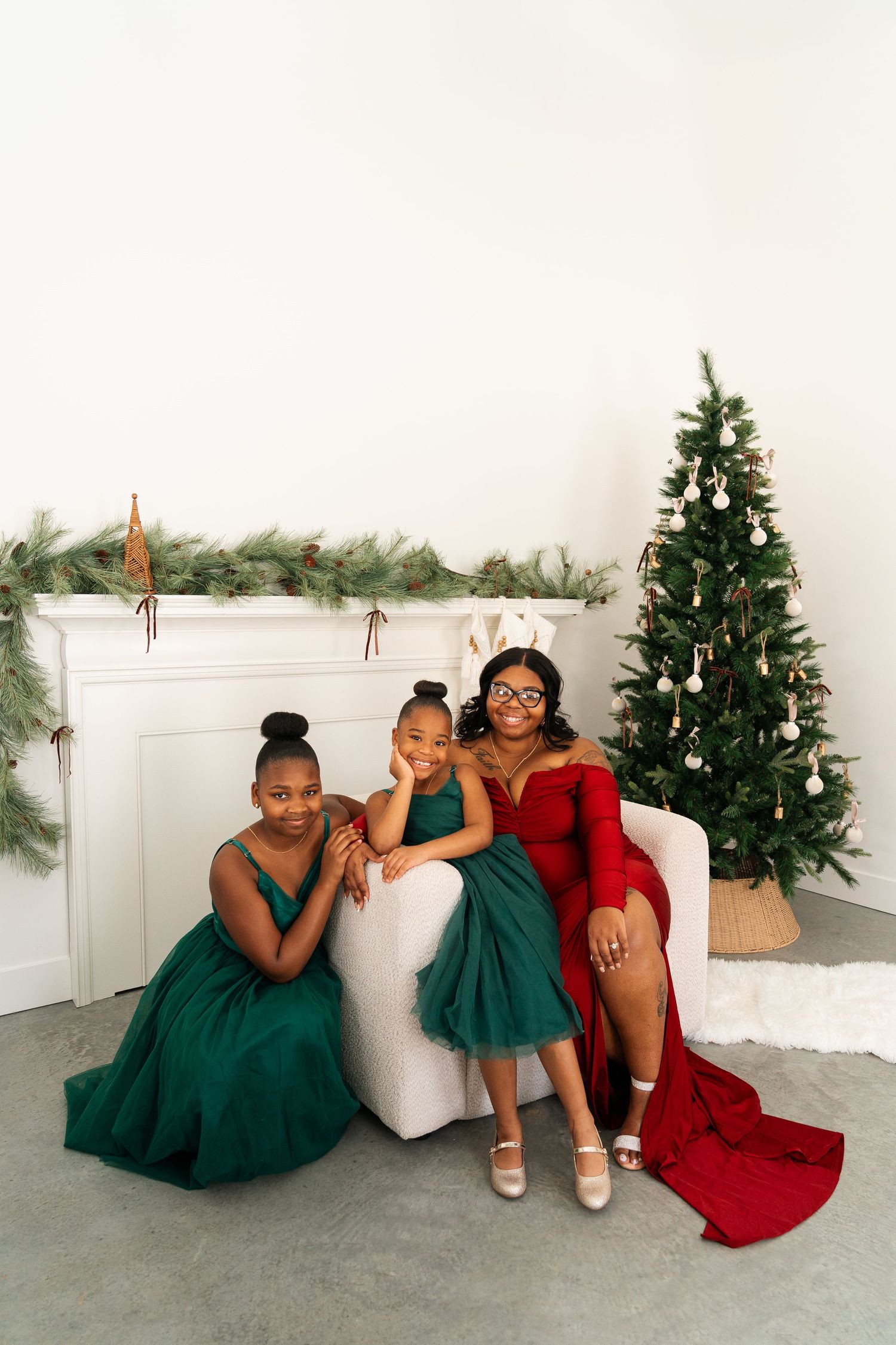 A family group poses on a white couch with Christmas decor and a decorated tree in the background.