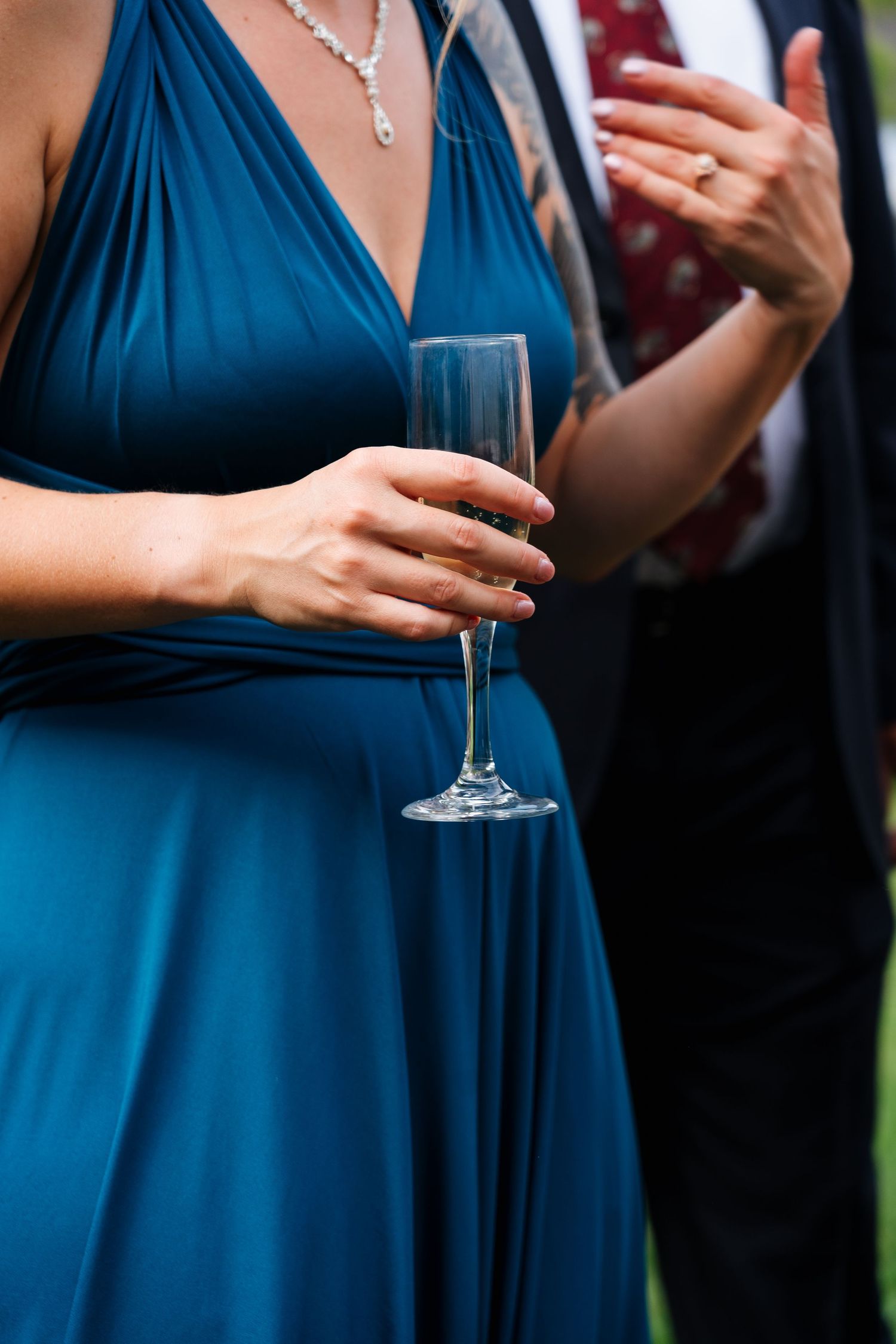 Close-up of bridesmaid in blue dress holding champagne glass during wedding reception.