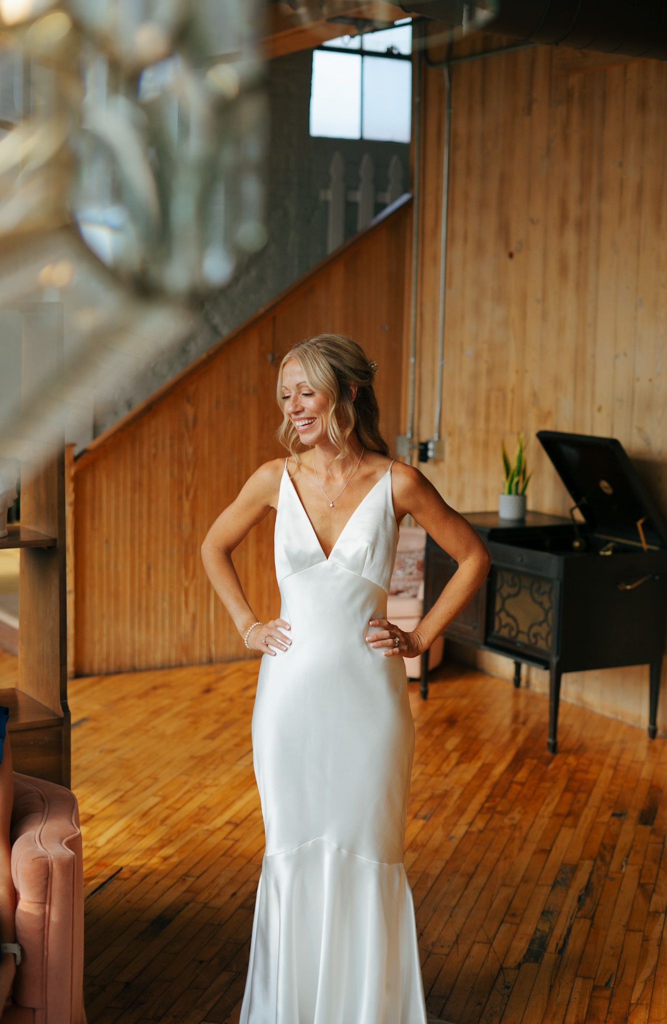 Person in a white dress dancing in a sunlit room with wooden floors.