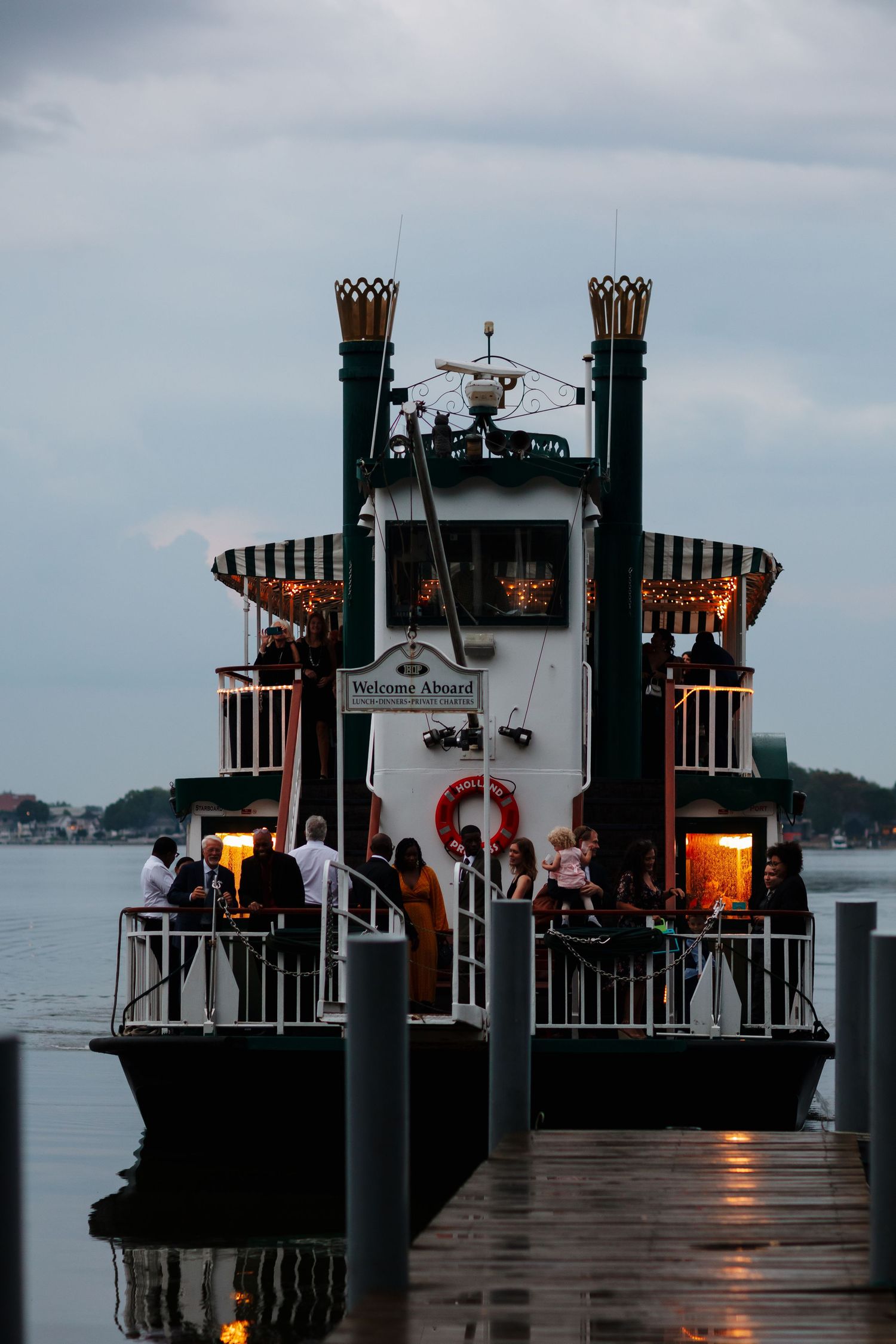 Illuminated riverboat dock at twilight during wedding celebration.