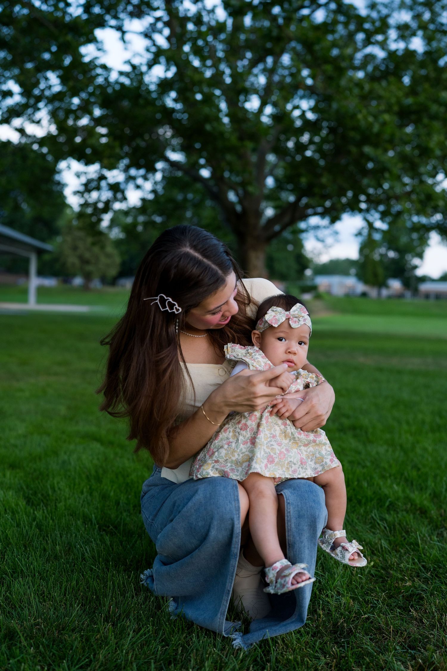 Mother and child sharing intimate moment on grassy field during sunset.