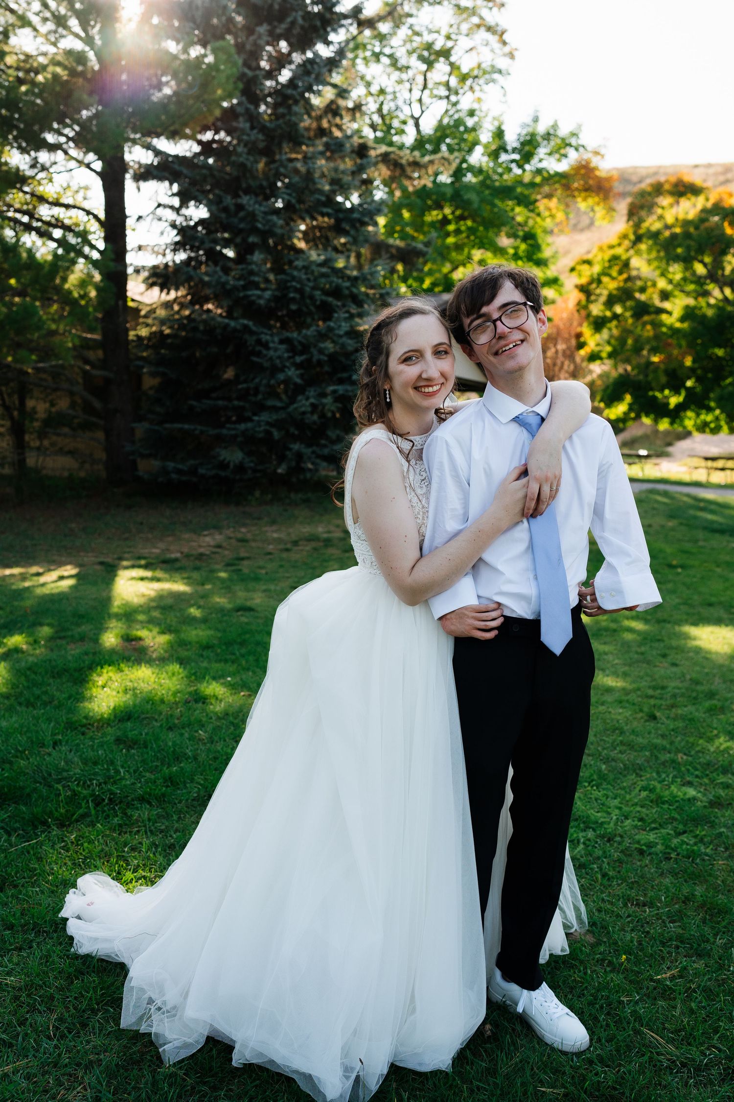 Couple shares joyful moments together on grassy lawn during wedding photoshoot.