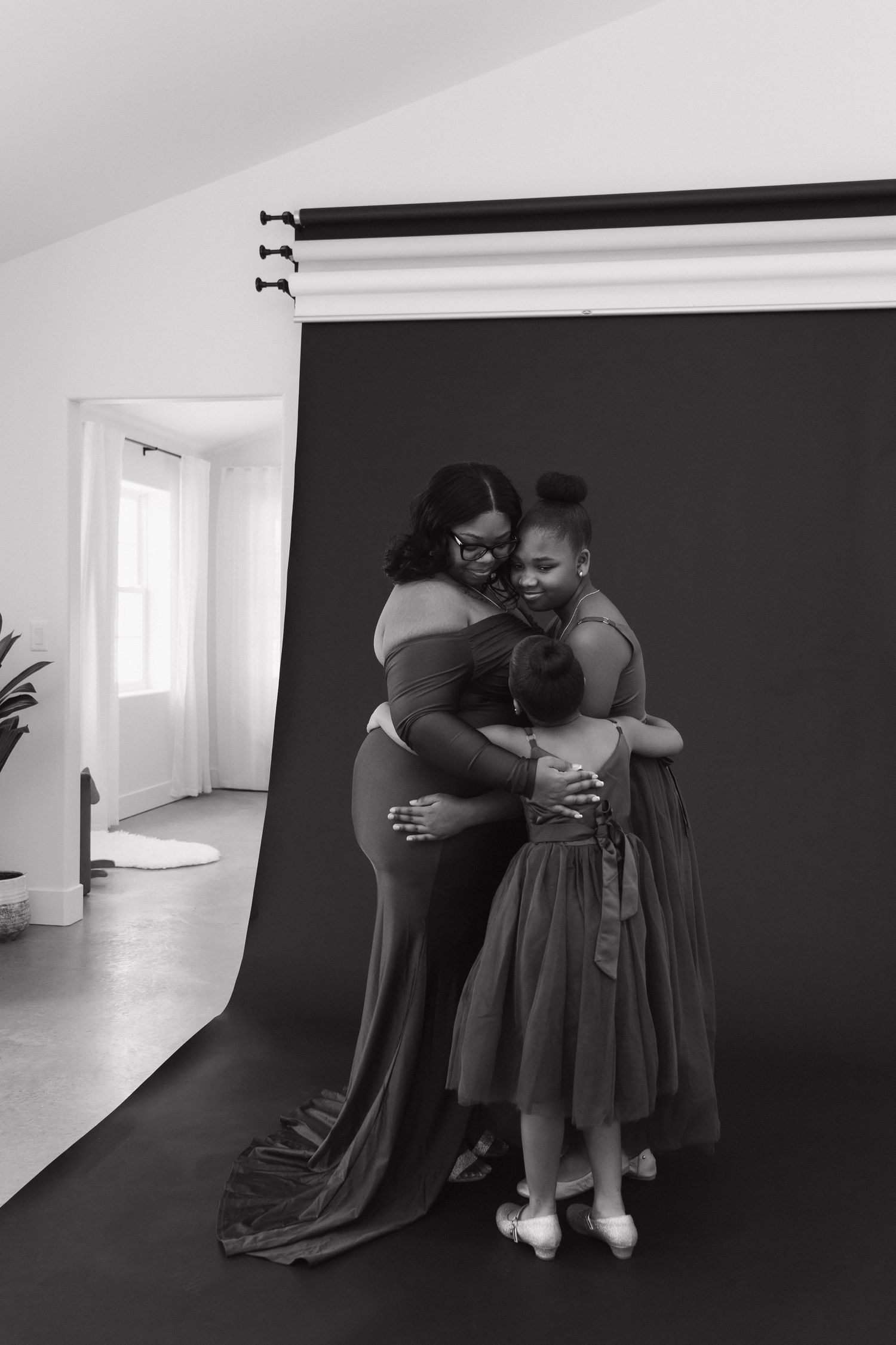 Two people share an emotional embrace in a photography studio with a black backdrop.