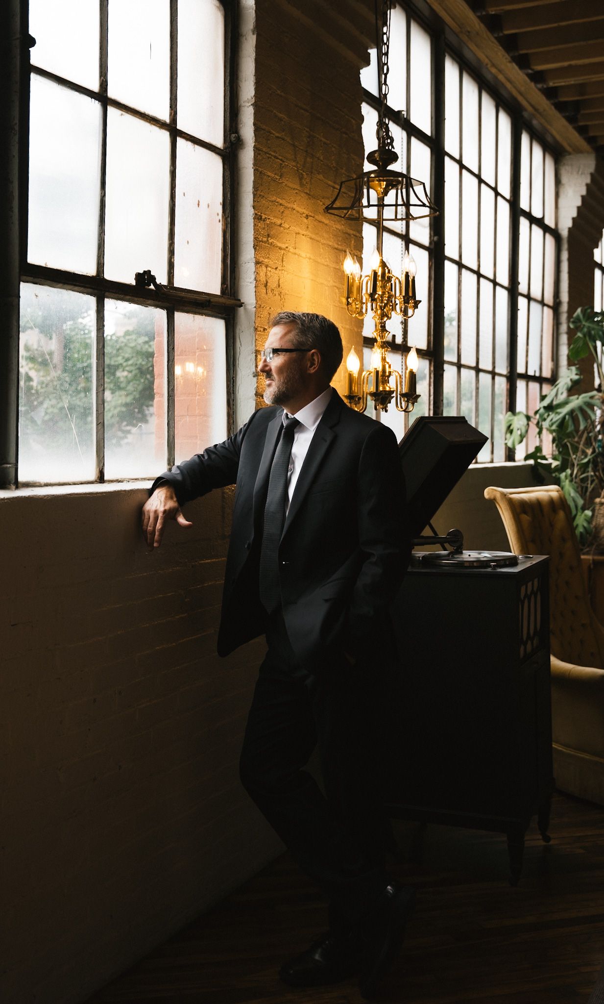 Dramatic silhouette of person in suit against large industrial windows.