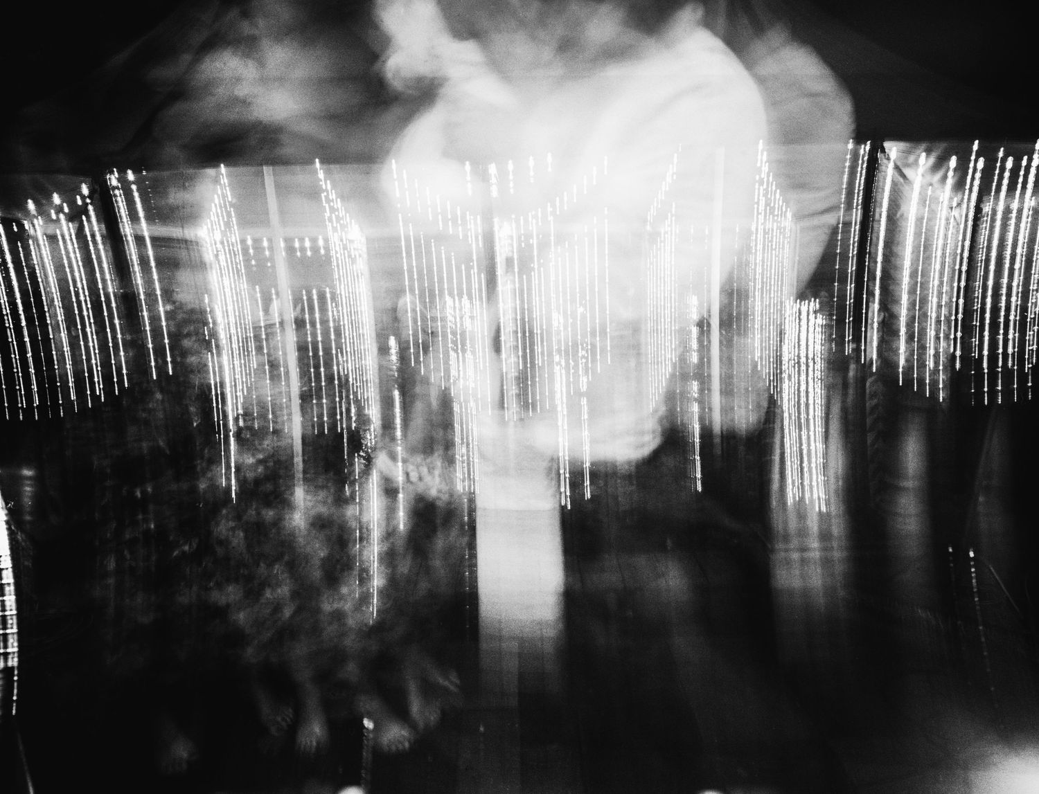 Abstract black and white long exposure photograph showing streaks of light against a dark background.