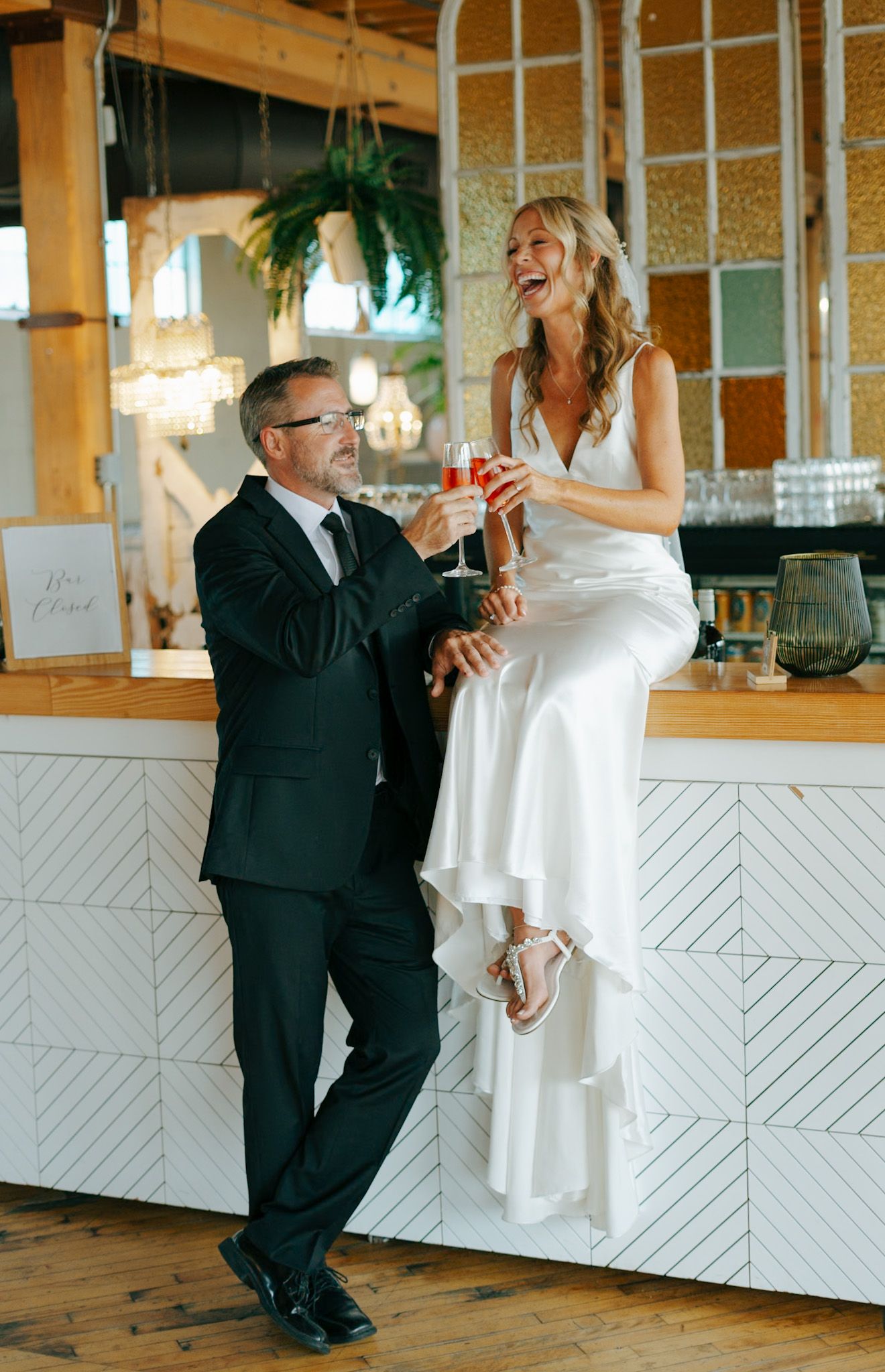 A couple dances together in a rustic venue with white geometric wall patterns.