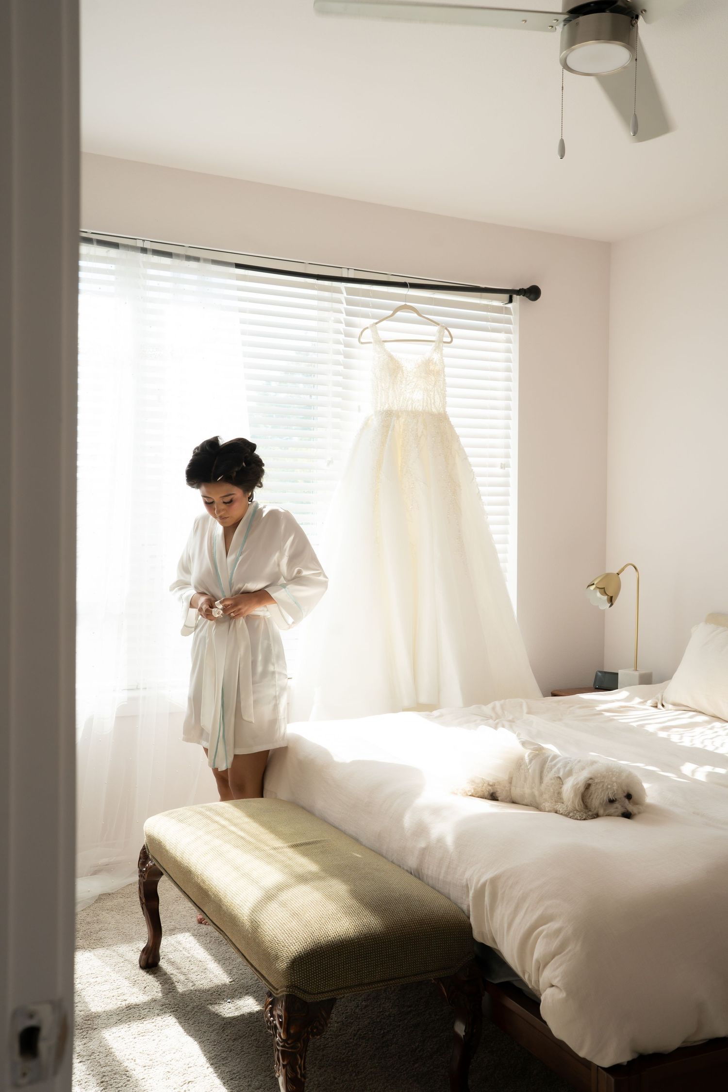 Bright minimalist bedroom scene with white bedding and natural light streaming through windows.