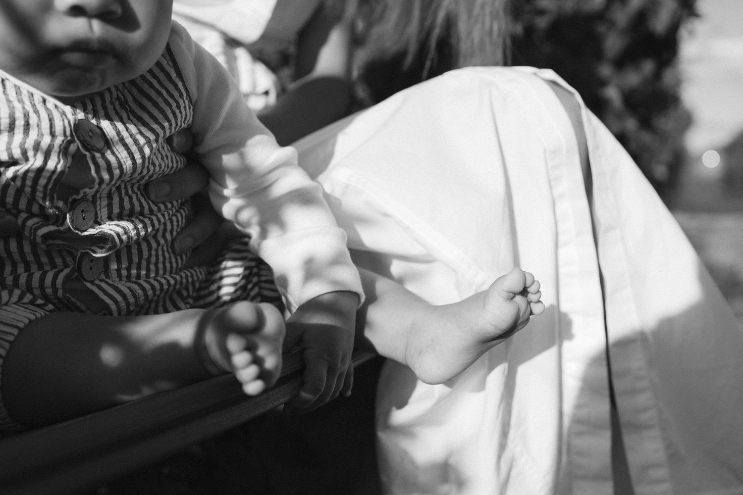 Black and white image of small hands reaching toward white fabric.