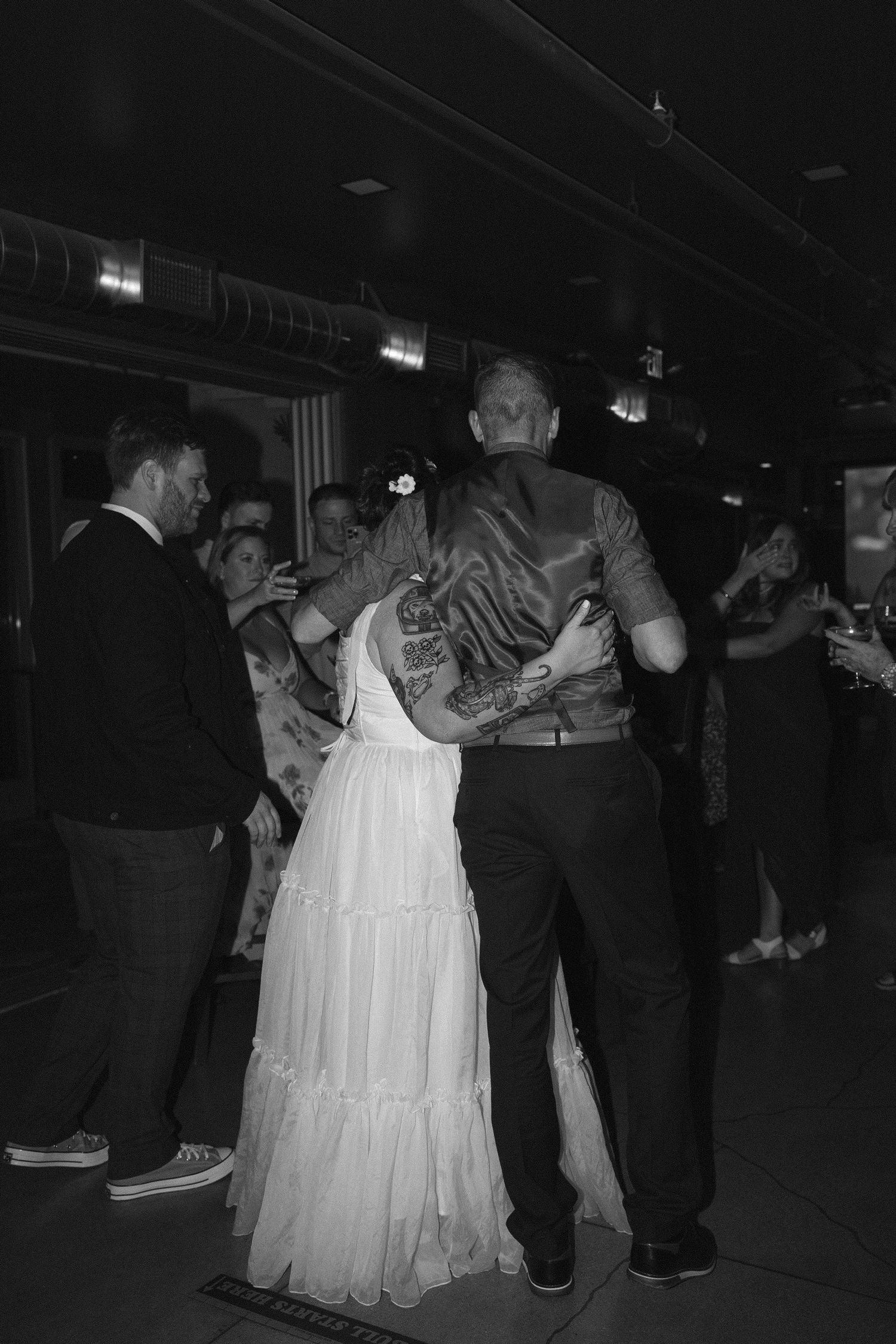 People dancing and socializing at a dimly lit reception or party venue.