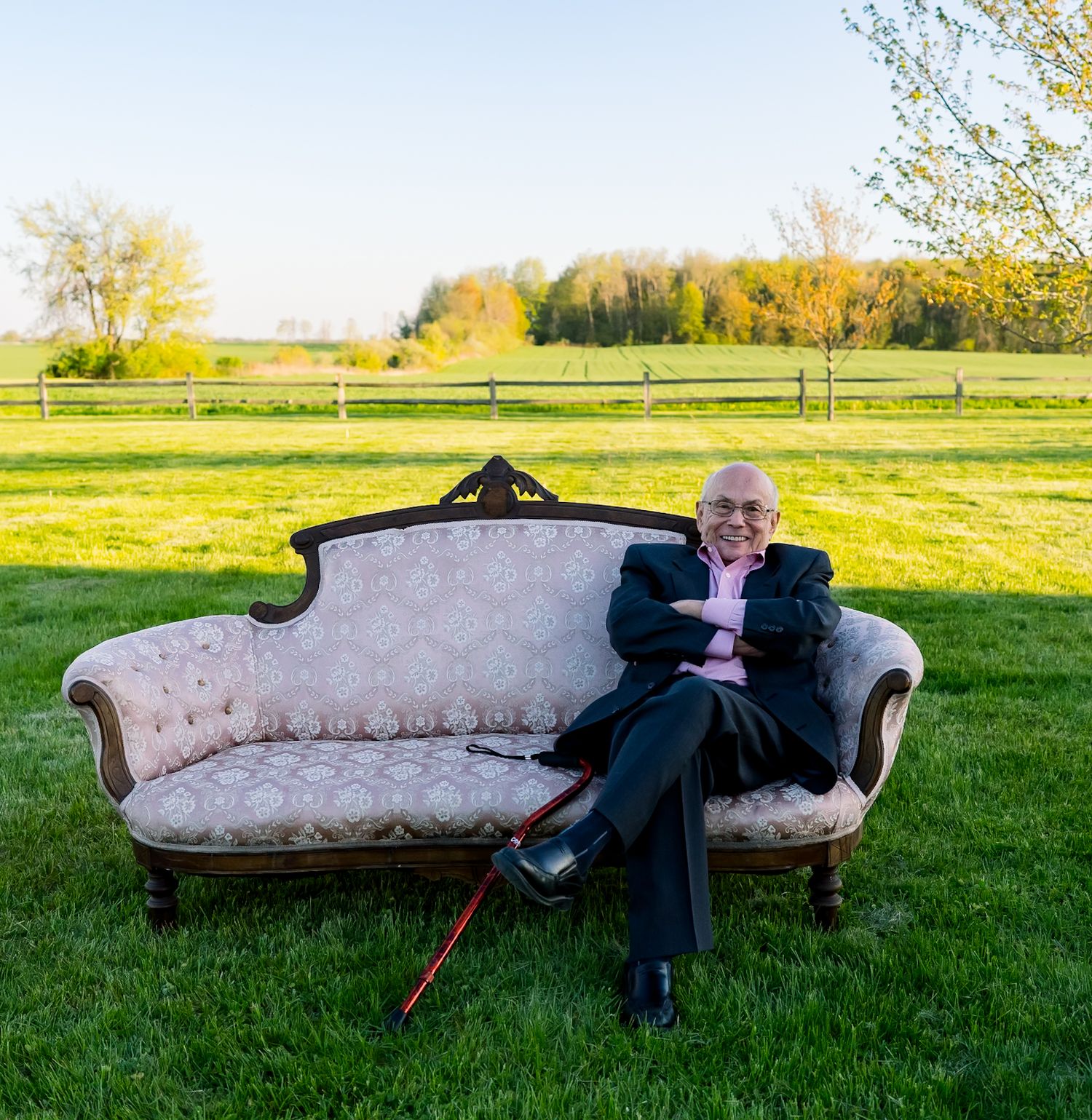 A vintage floral sofa sits in a green field during golden hour.