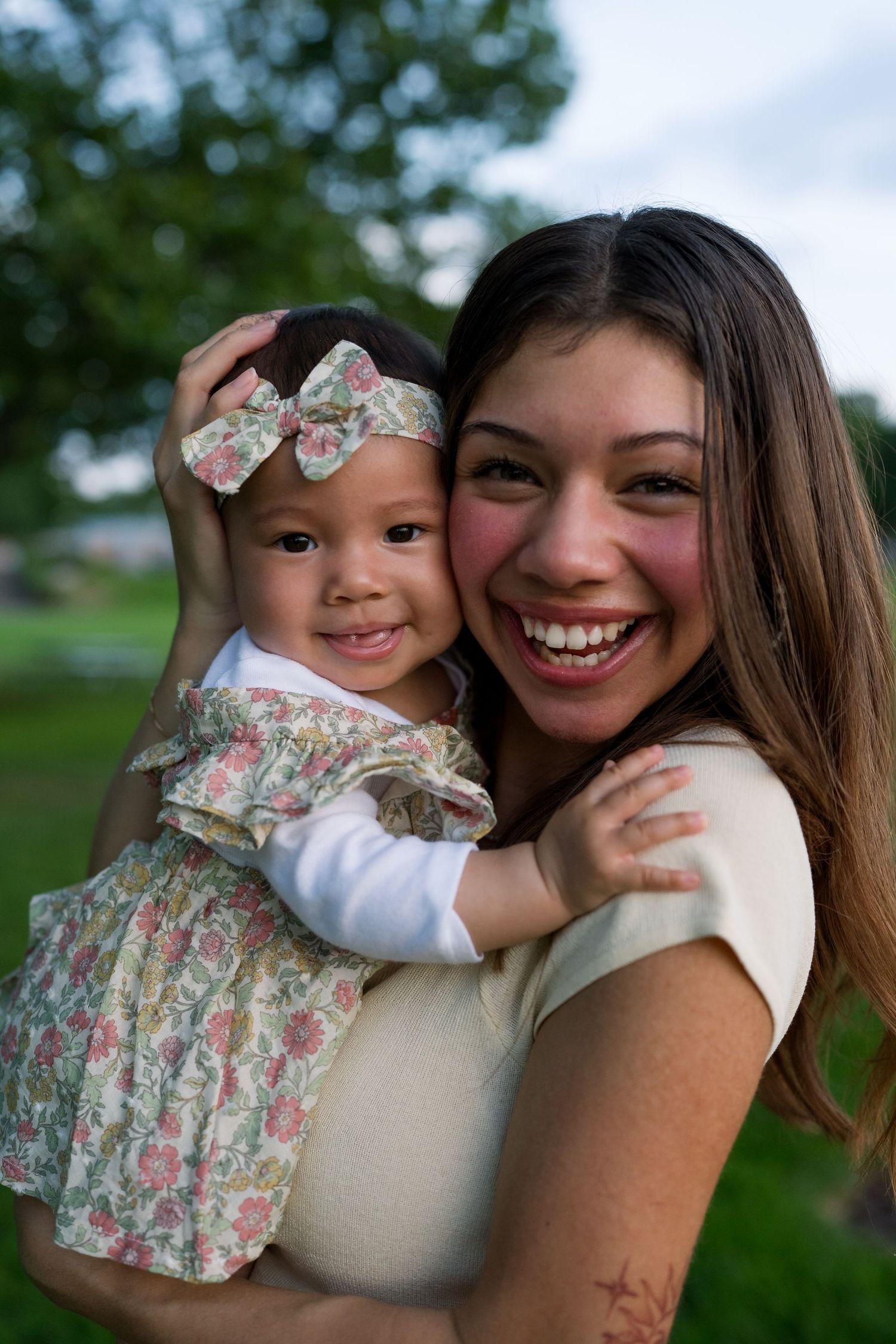 Mother and baby in matching outfits share happy moment in outdoor park setting.