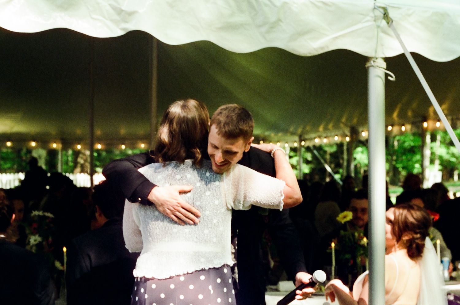 A romantic slow dance moment under twinkling lights at an evening outdoor reception.