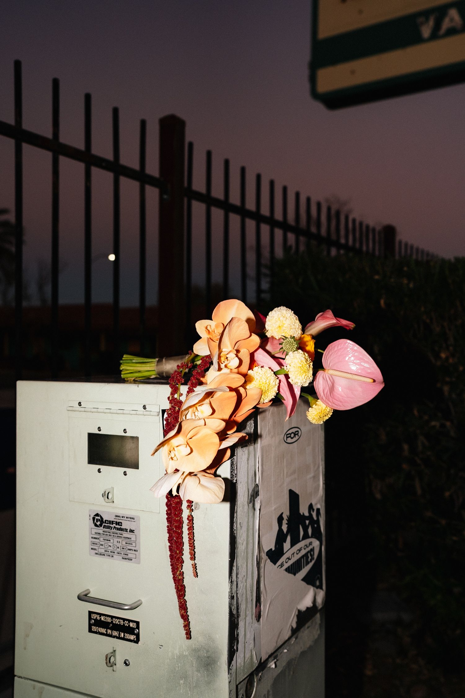 Discarded toys and objects arranged on a white utility box at dusk.