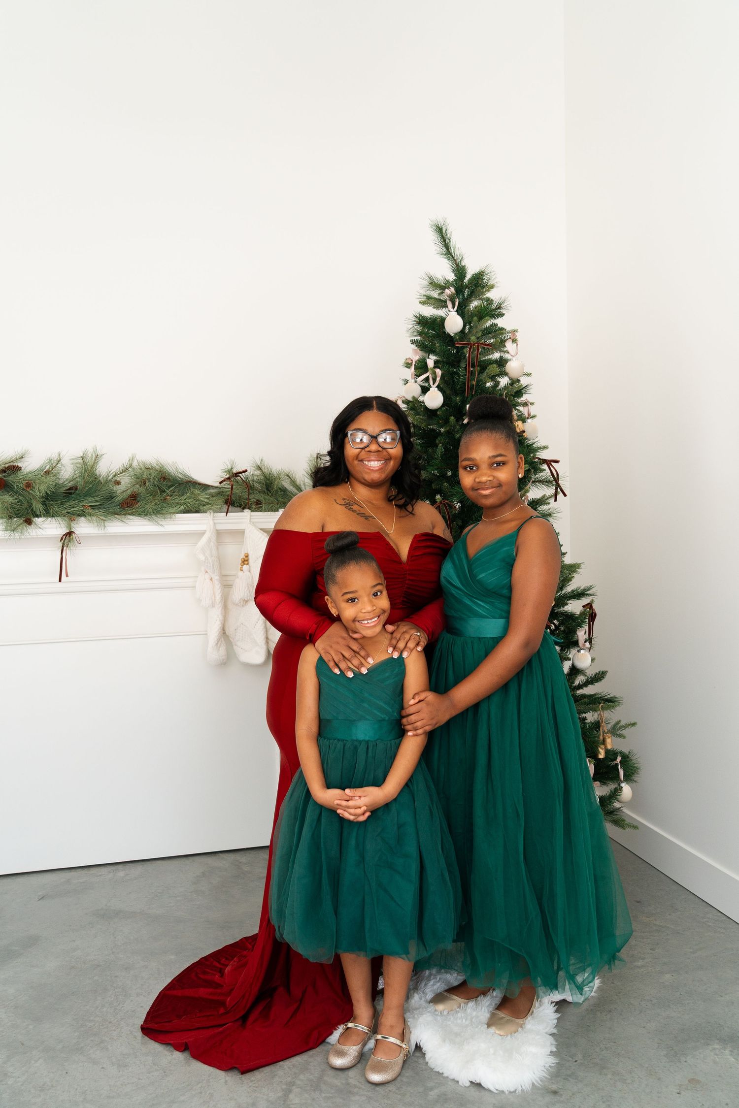 Festive family photo with Christmas tree and coordinated red and green formal attire.