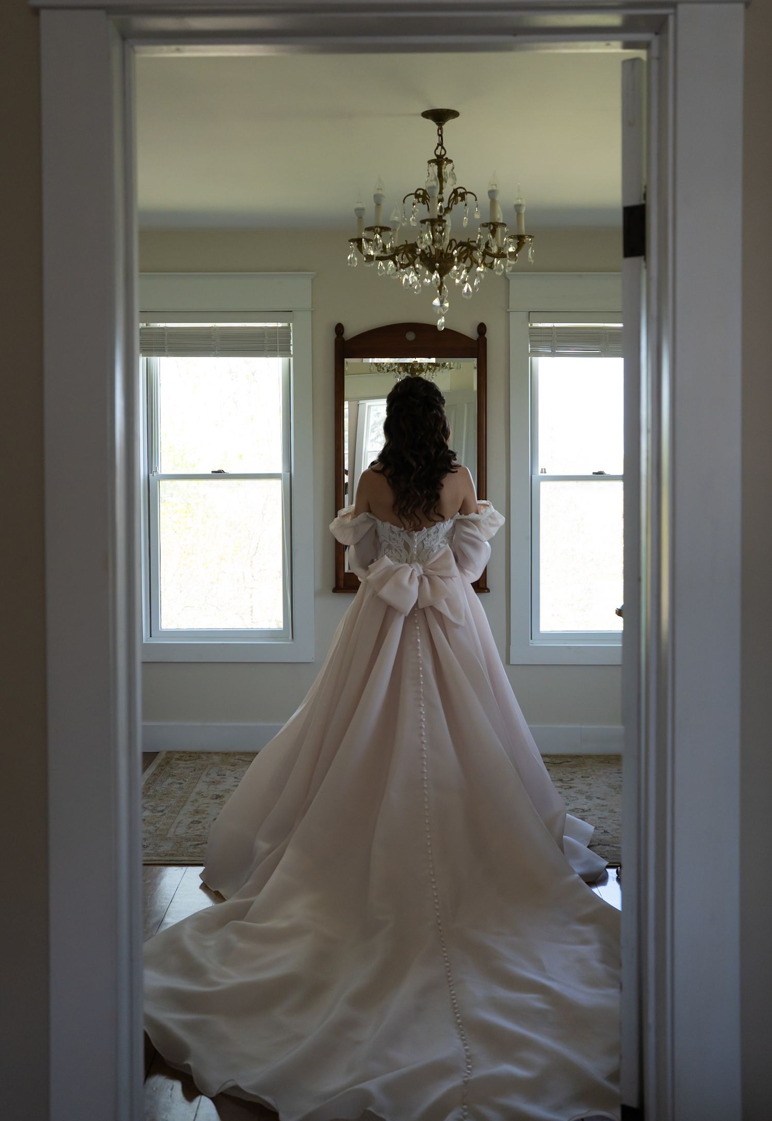 Elegant white wedding gown with dramatic train displayed in a bright dressing room.