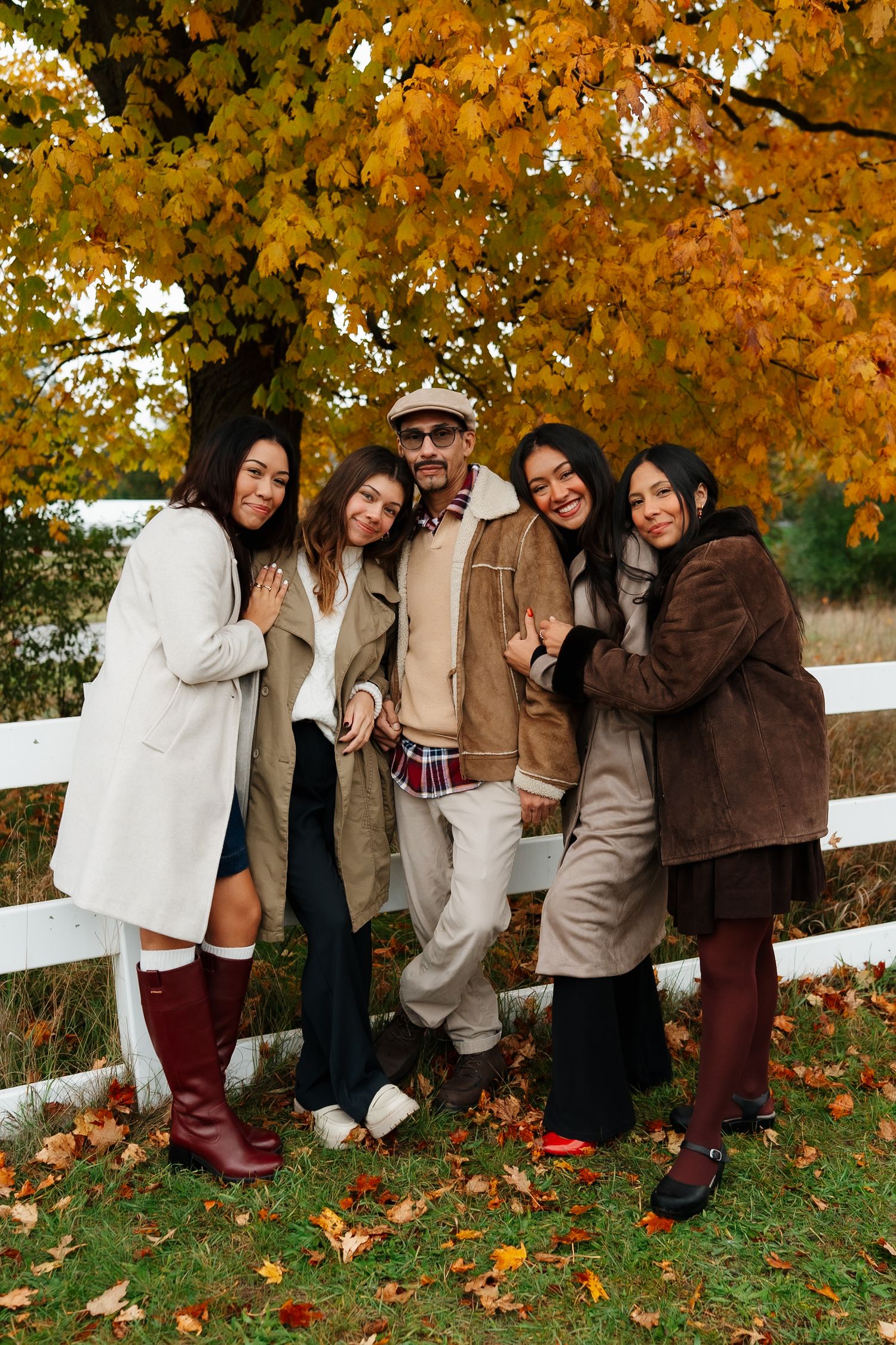 Group photo against white fence with vibrant fall foliage in background.