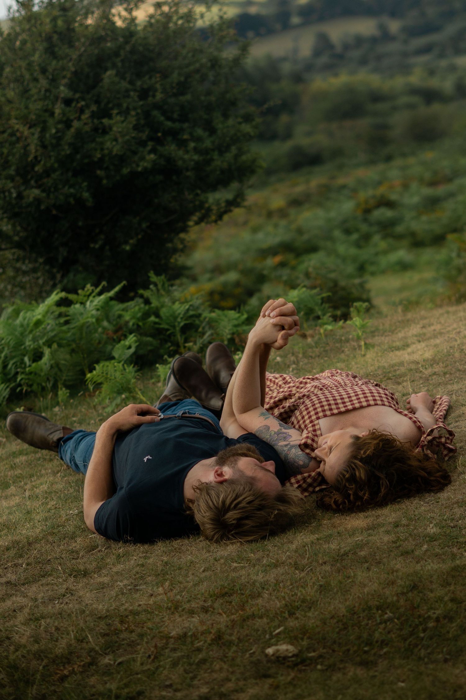 Couple laying in the grass during their engagement photoshoot on Dartmoor National Park, Devon