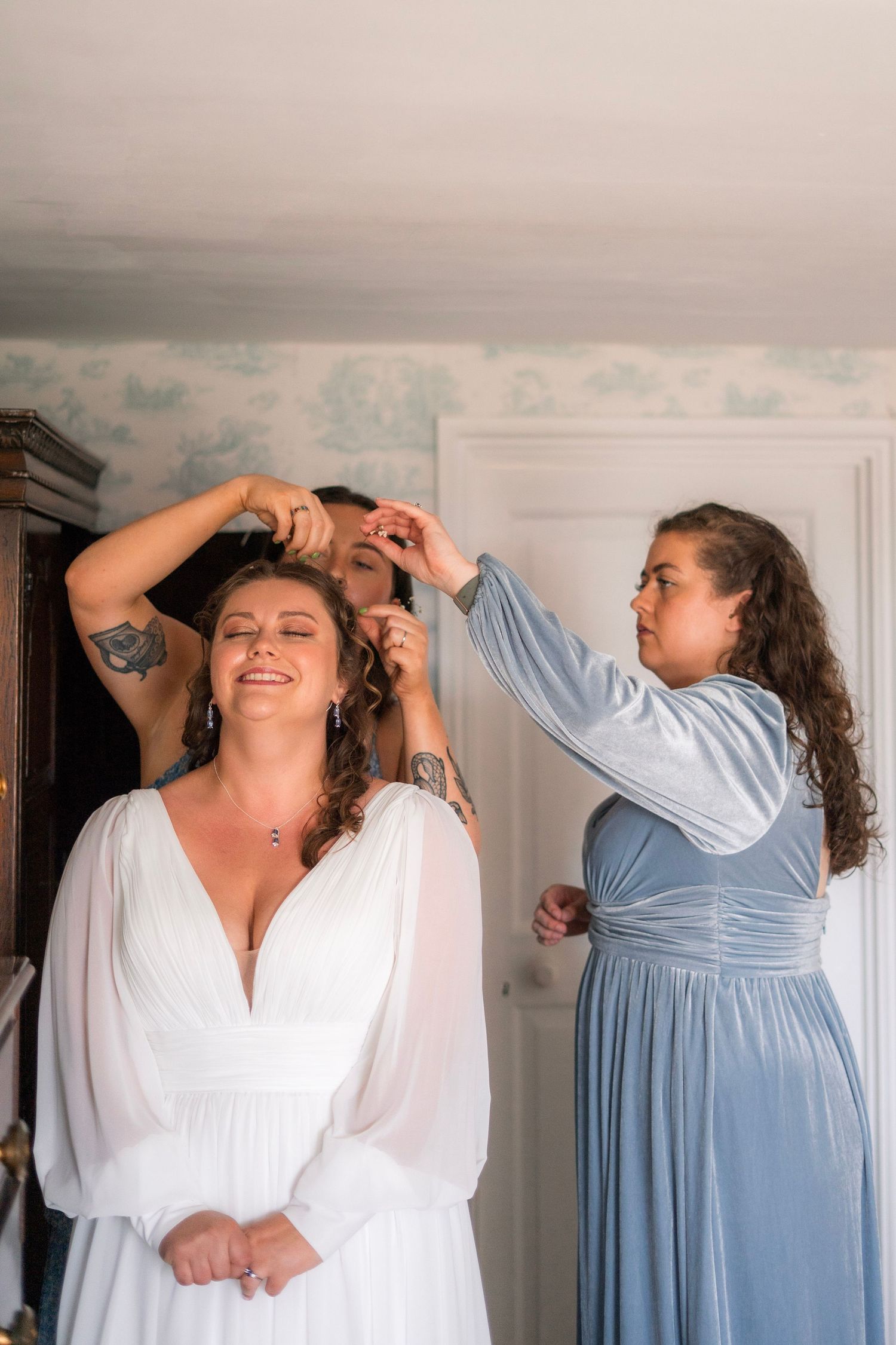 Bridesmaids helping wlw bride get ready, with dress from Wed2B