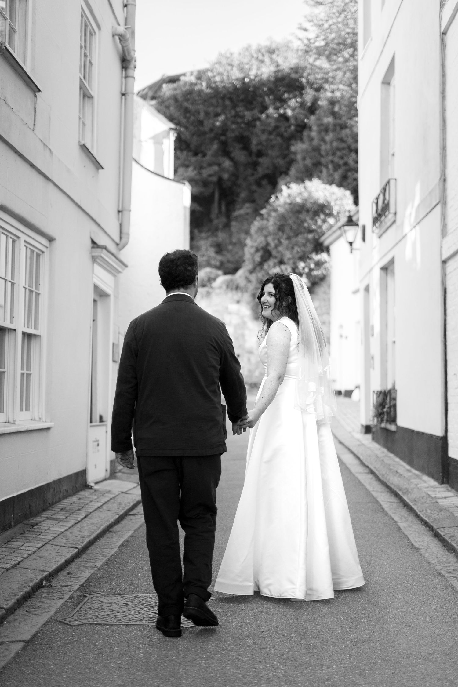 Bride and groom walking through Cornish village on their wedding day