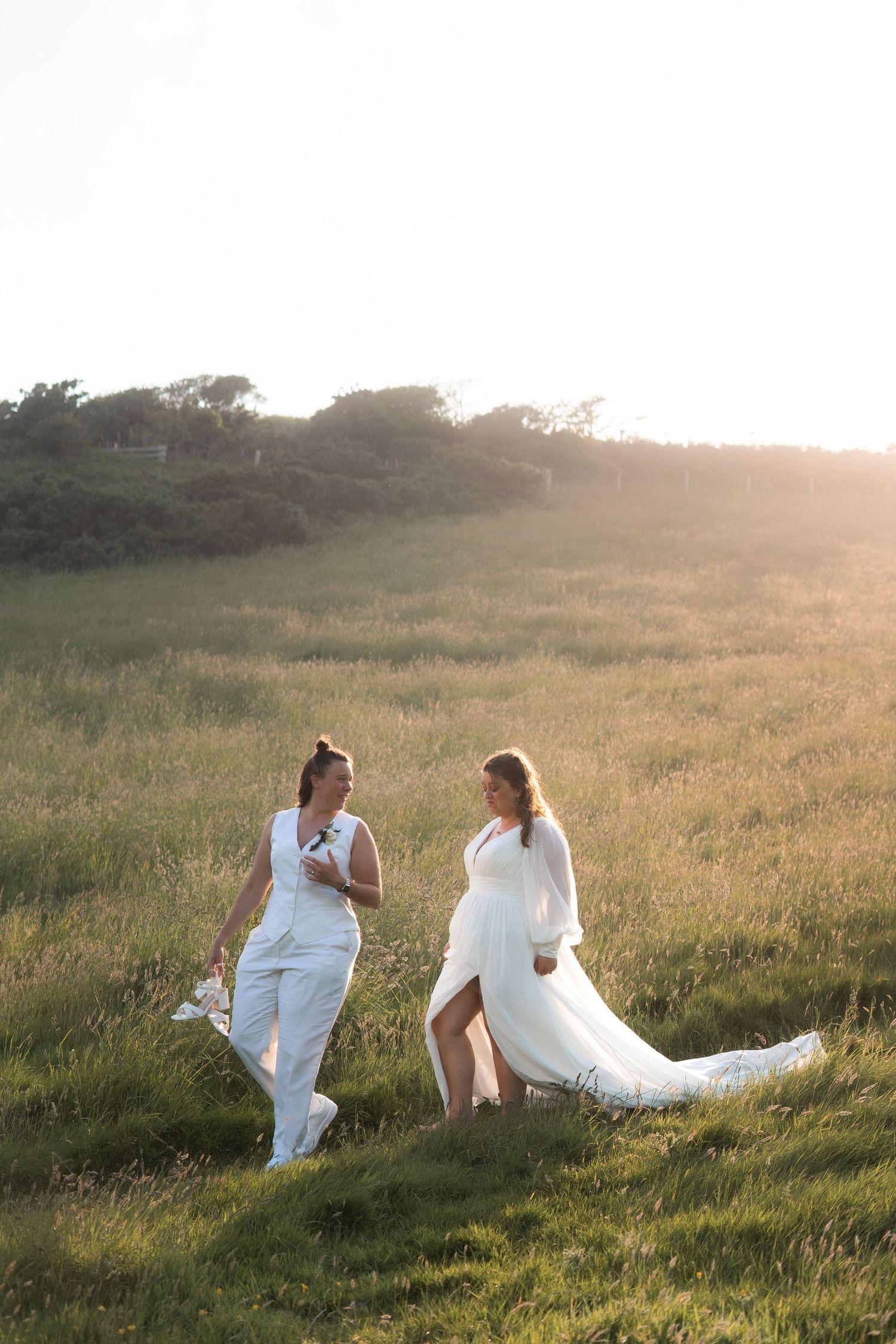 Bride and bride wearing Web2B and King and Allen , walking along the Cornish cliffs near Tredudwell Manor