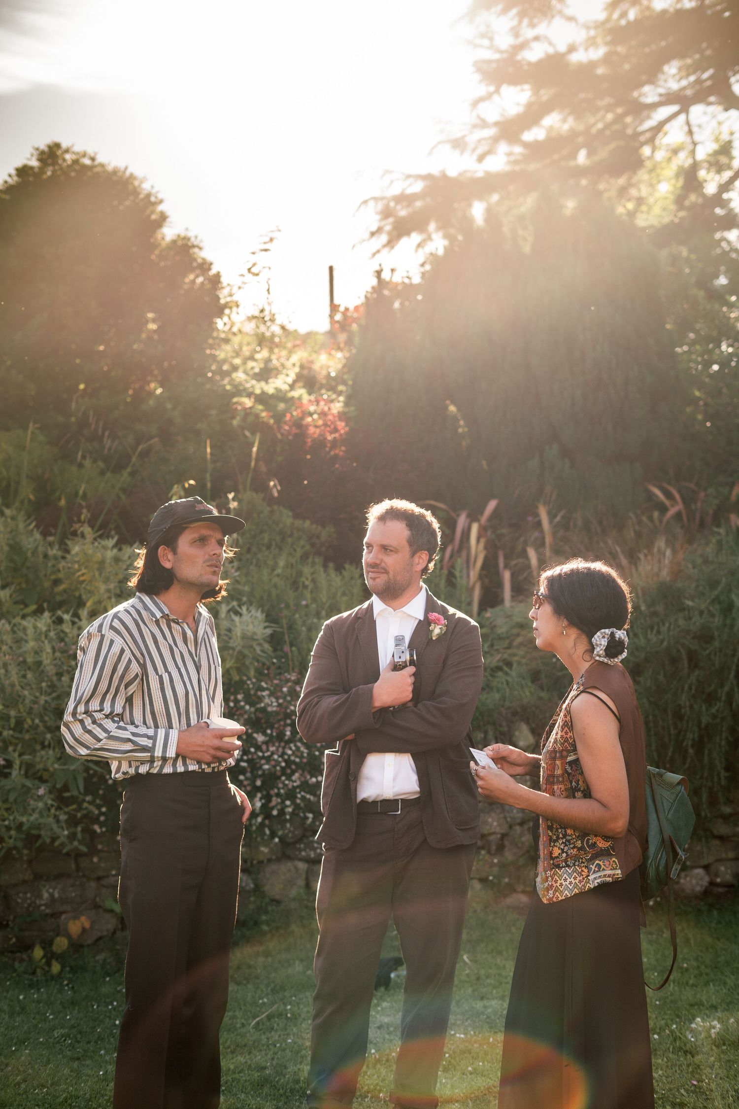 Groom chatting with wedding guests at golden hour