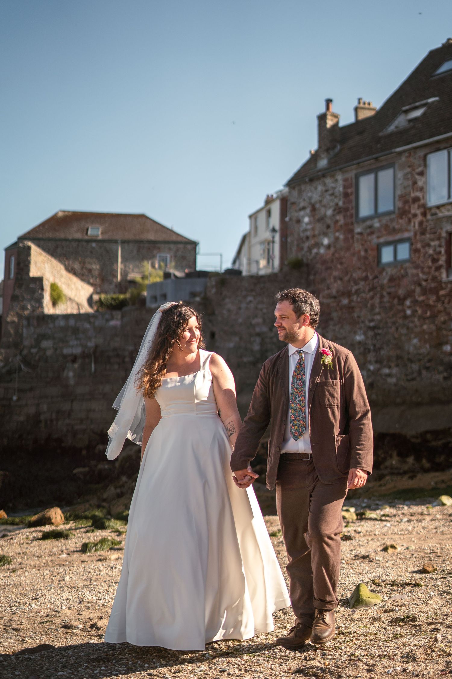 Bride and groom enjoying a sunny beach stroll in Cornwall