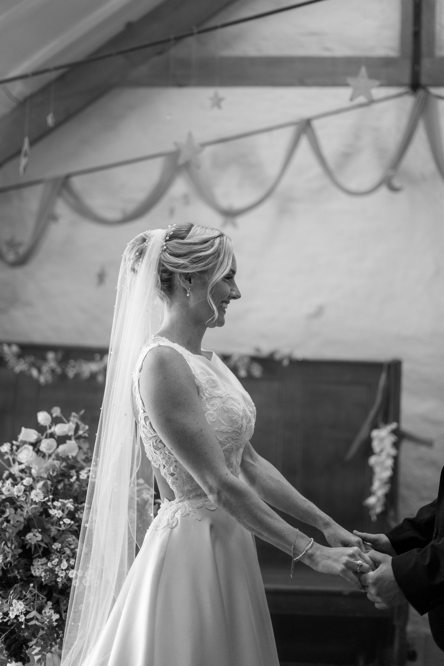 Black and white photo of bride during her ceremony at Trerice National Trust. Dress from Bliss Bridal Gowns, flowers by Tregarrian Farm
