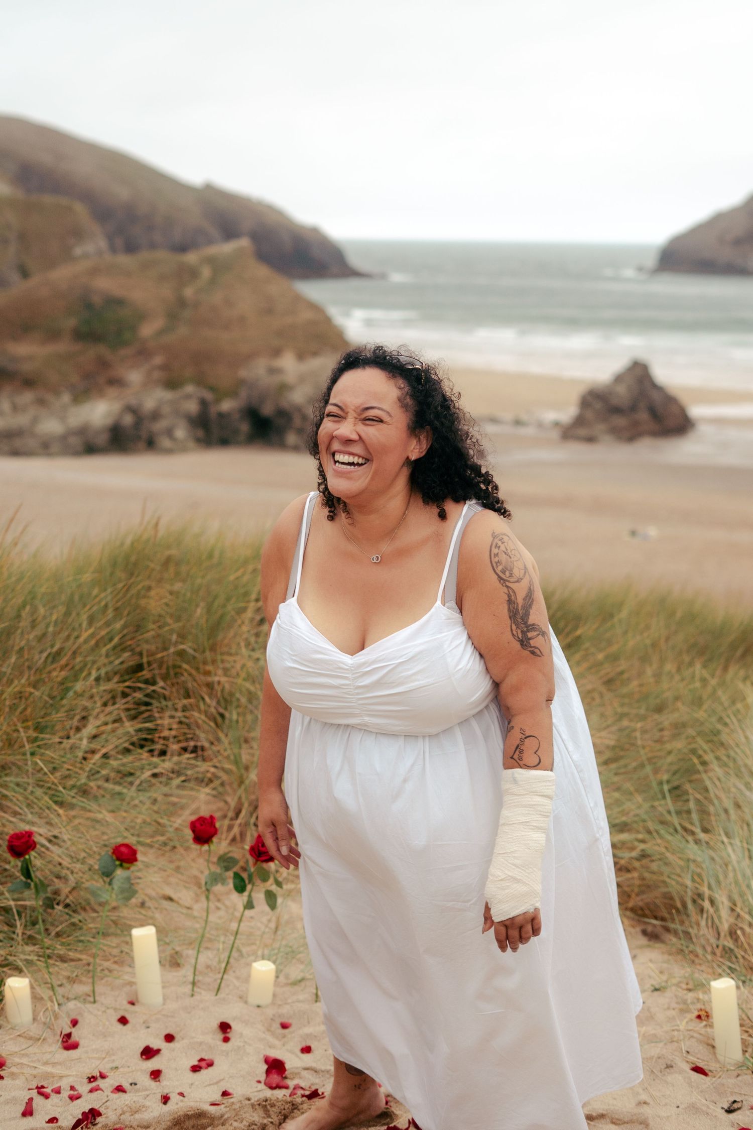 Candid photo of a woman laughing after getting engaged on the beach in Cornwall