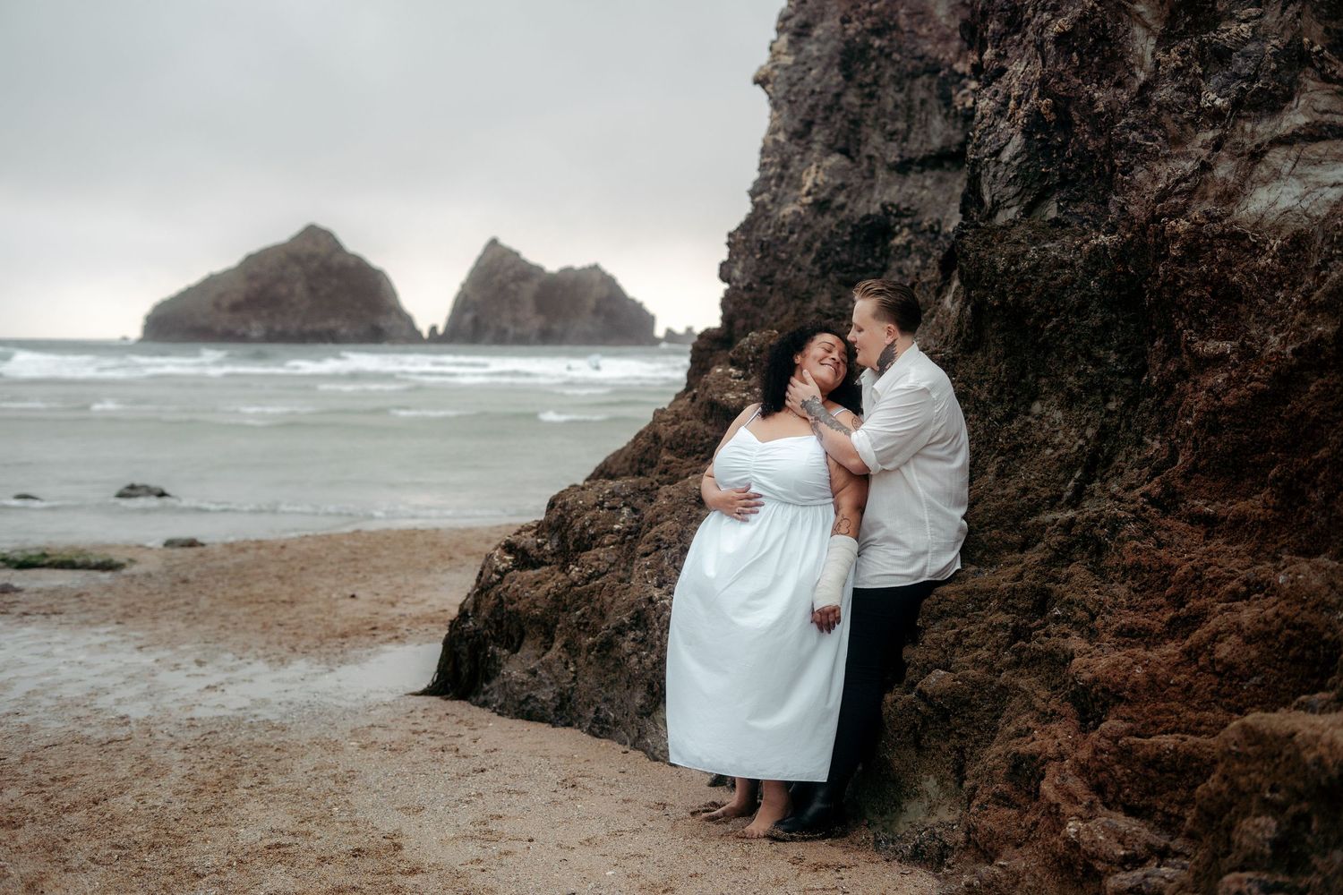 A lesbian couple cuddling on the beach in Cornwall after getting engaged, photographed by an LGBTQ+ wedding photographer