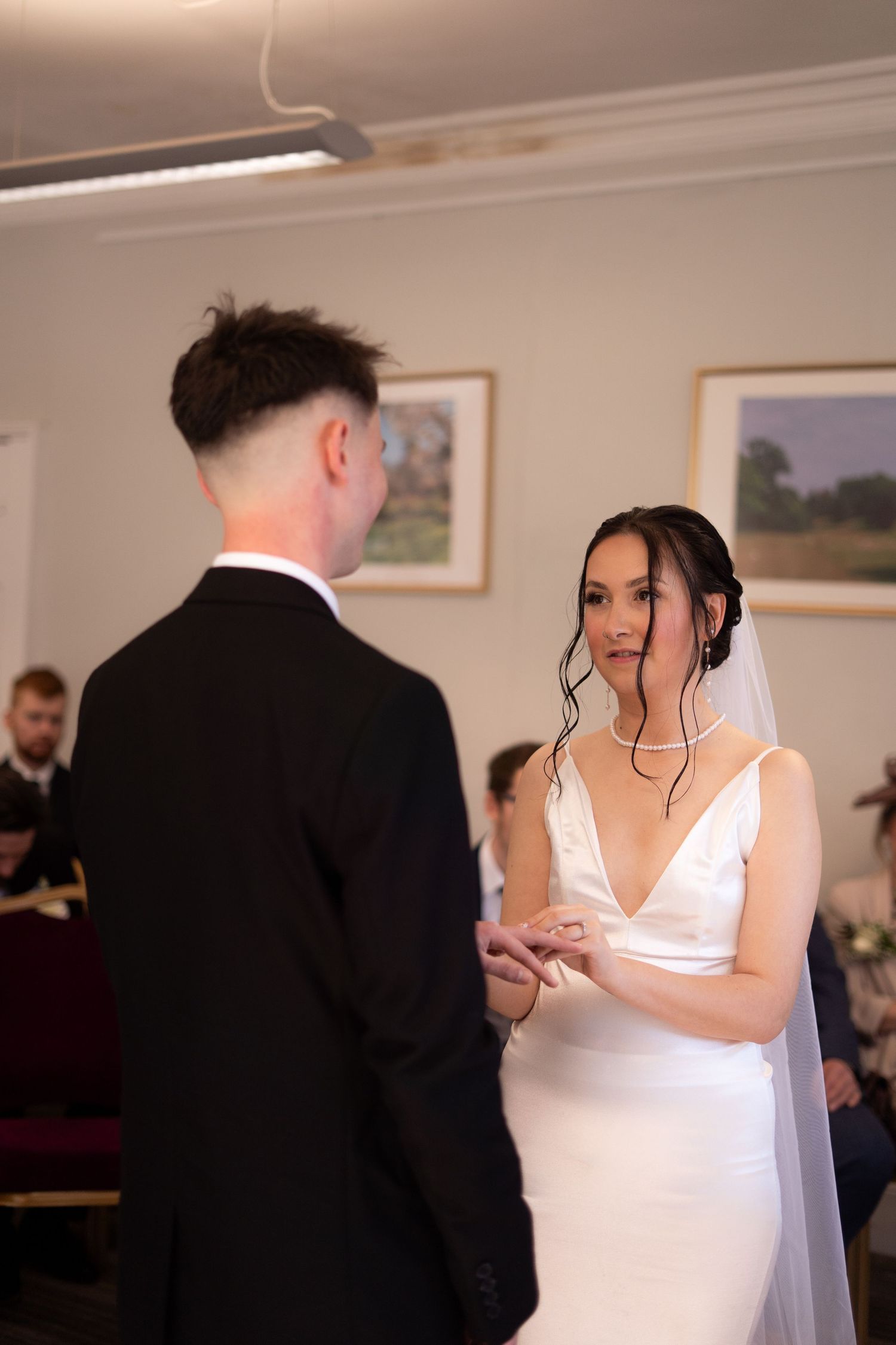 Candid photo of bride looking at groom during wedding ceremony in Cockington Court registry office